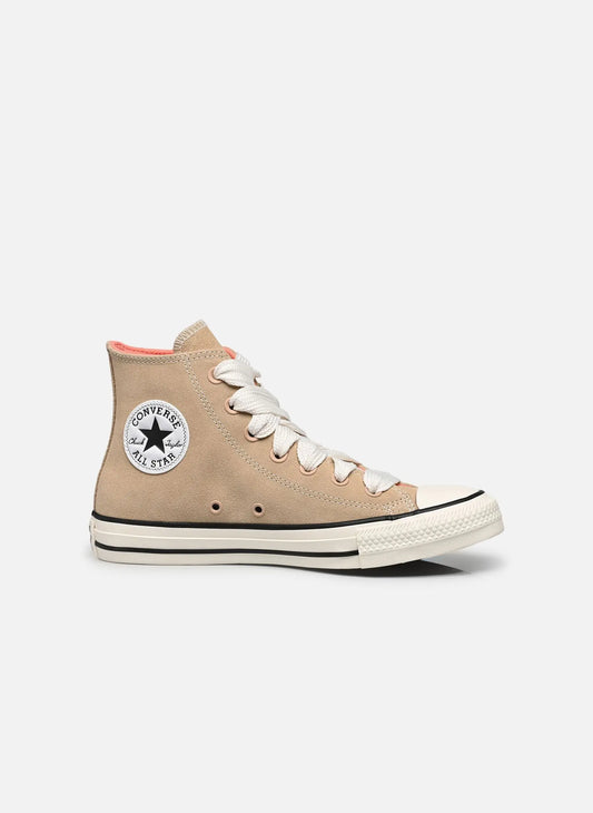 Baskets montantes beiges en daim de Converse, avec des lacets blancs et une semelle à rayures noires.