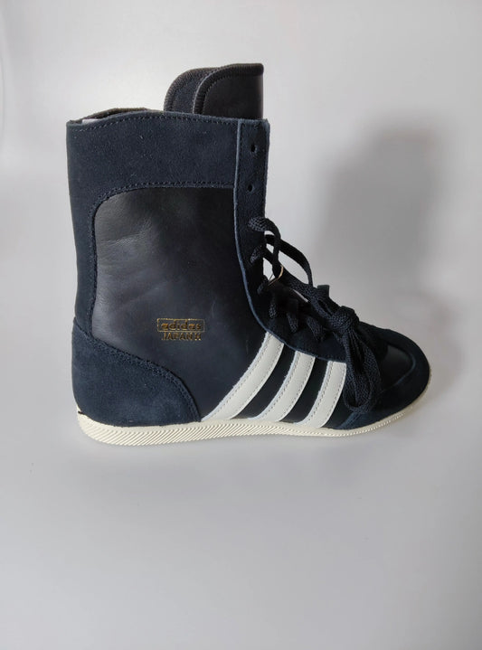 Baskets montantes noires et blanches Adidas, avec des lacets et des trois bandes blanches sur le côté.