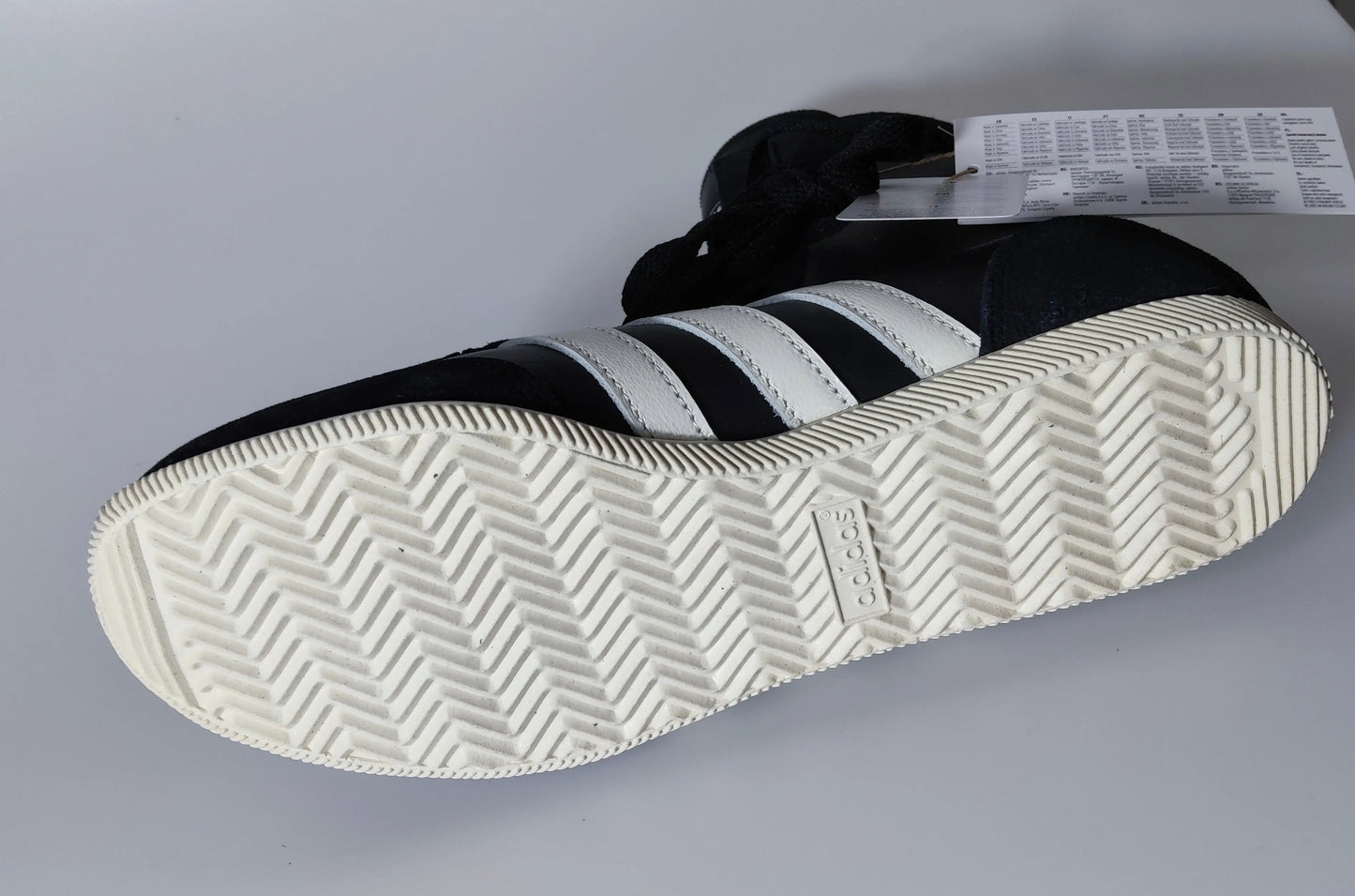 Basket montante noire et blanche par Adidas, avec semelle à chevrons crème.