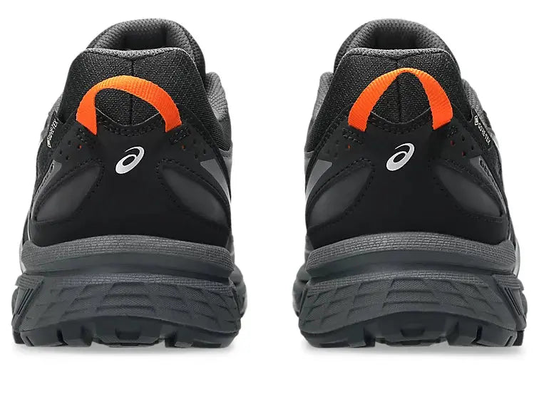Chaussures de trail noires par Asics, vue arrière avec logo blanc et détails orange.