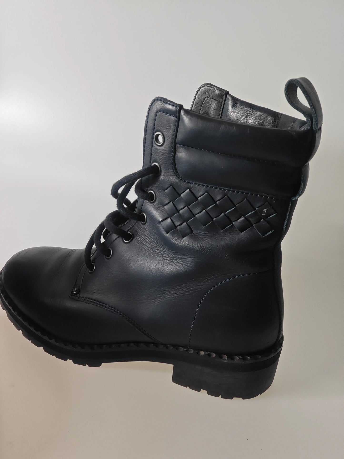Bottines en cuir noir tressé de Bottega Veneta, avec lacets noirs et tirant à l'arrière, en vue latérale.