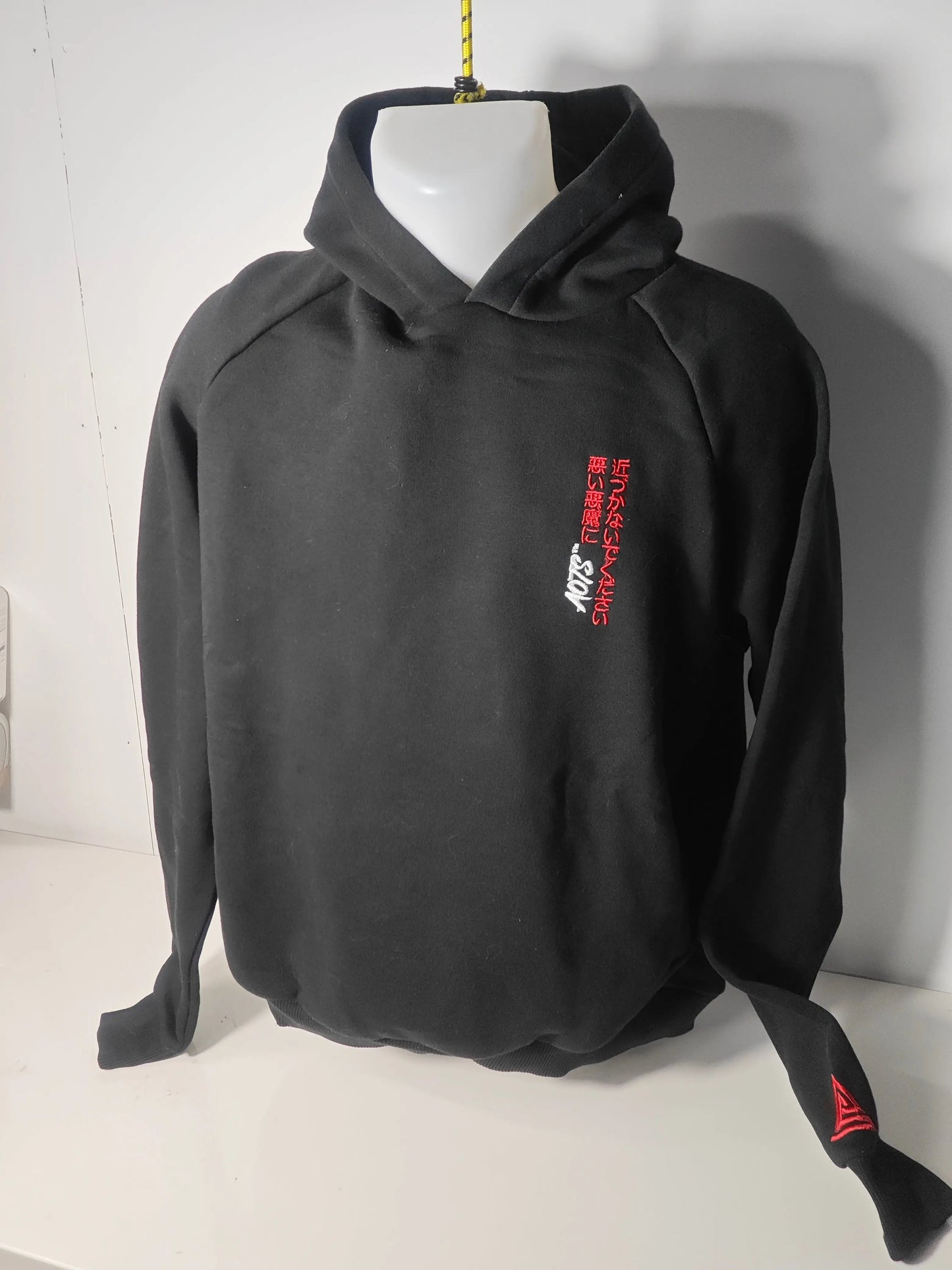 Sweat à capuche noir à broderie japonaise de AOTS, avec un motif rouge sur la manche.