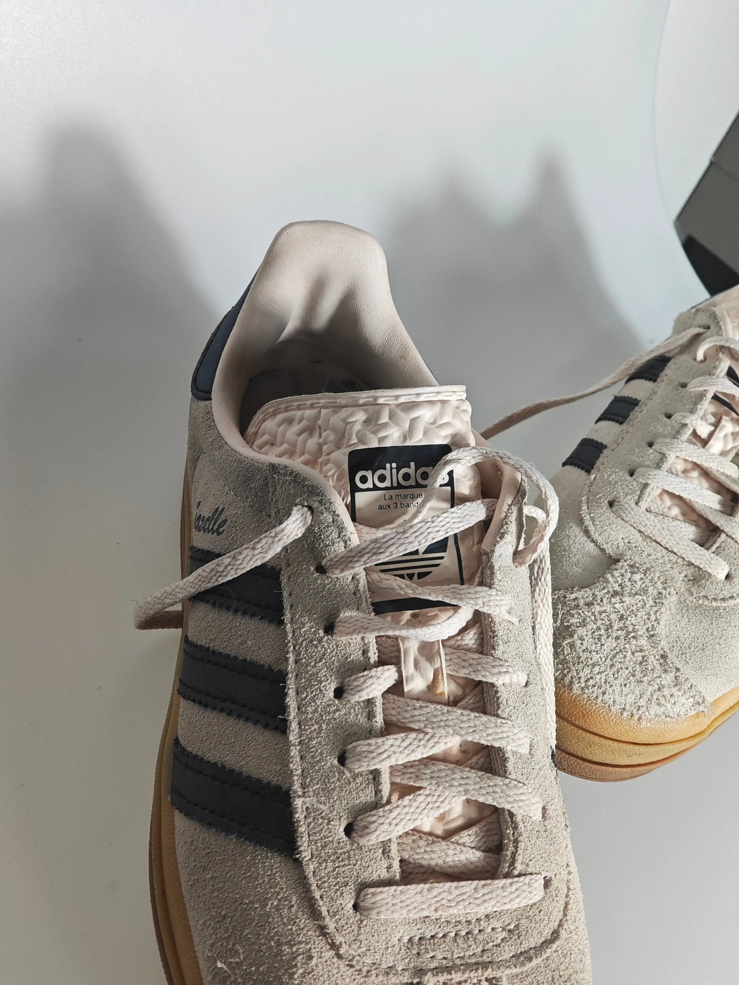 Baskets Gazelle en daim beige, édition spéciale par Adidas, avec les trois bandes foncées sur le côté.