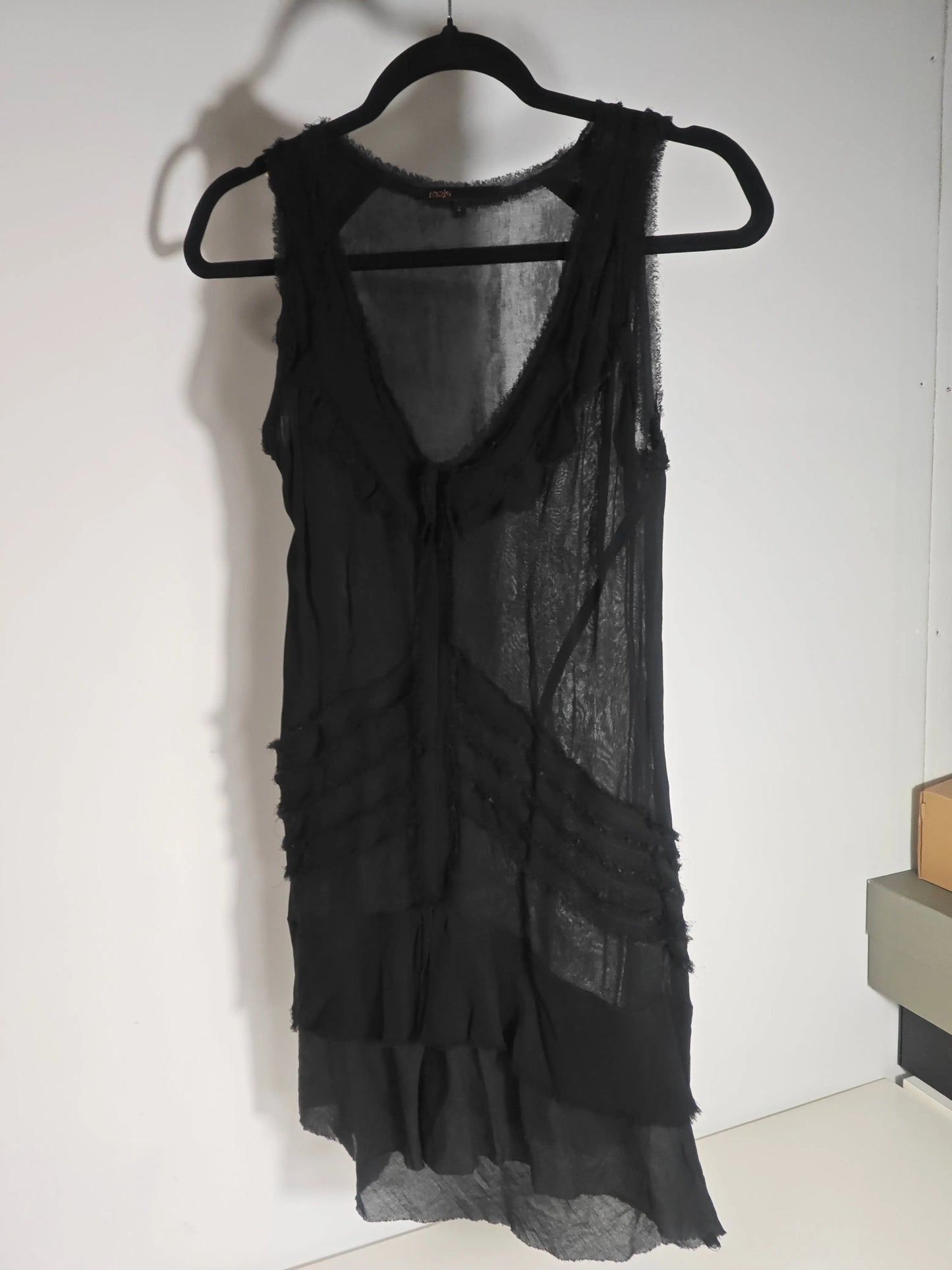 Robe noire fluide de Maje, coupe asymétrique avec détails à volants pour un look bohème chic.