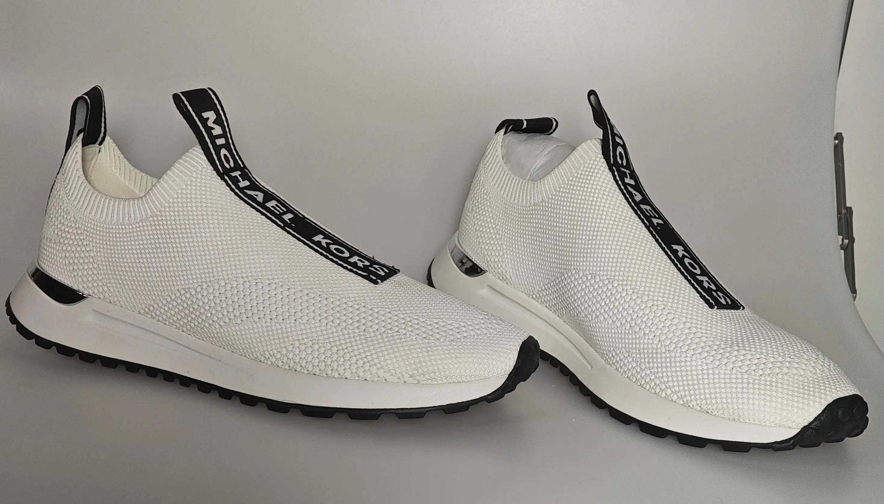 Baskets blanches en maille extensible de Michael Kors avec des accents noirs et une semelle blanche.