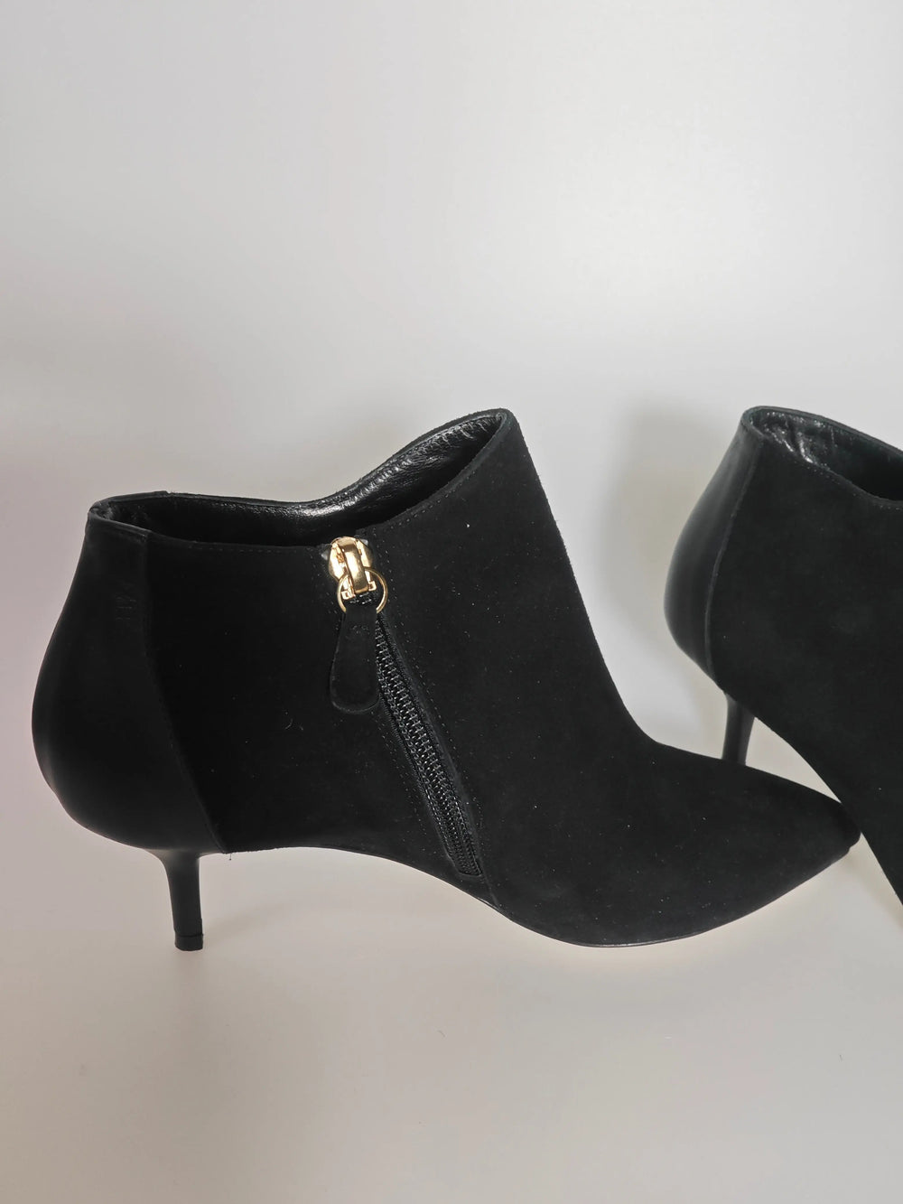 Bottines en daim noir de Repetto avec fermeture éclair dorée sur le côté en vue latérale.