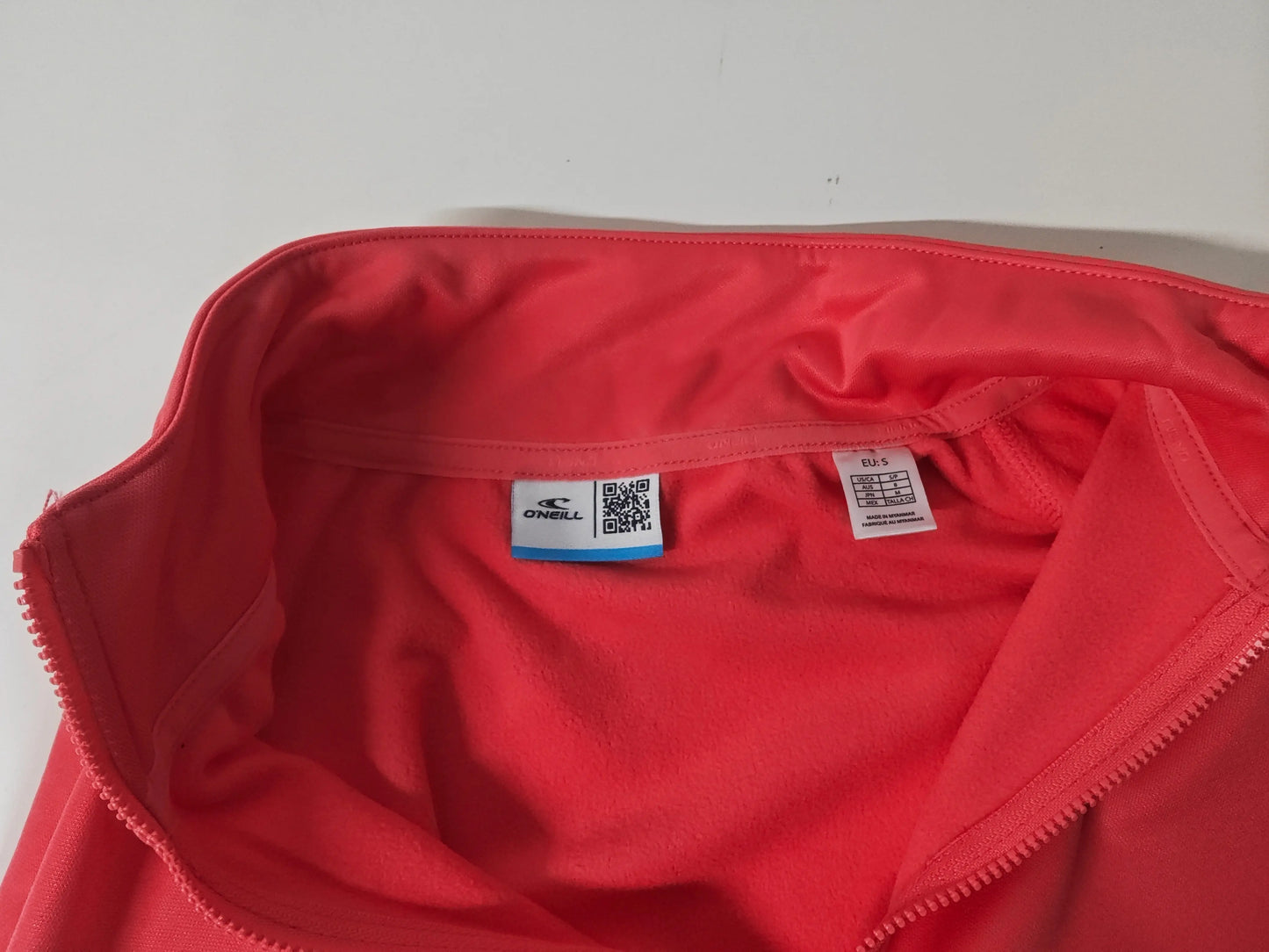 Veste rose corail de O'Neill, montrant l'intérieur en molleton et l'étiquette de taille.