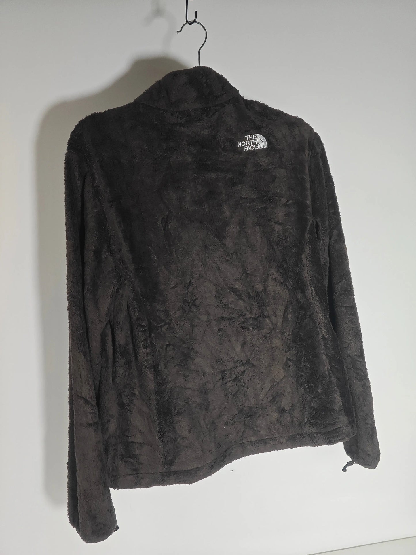 Veste polaire marron en pilou de The North Face, suspendue sur un cintre noir, vue de dos.