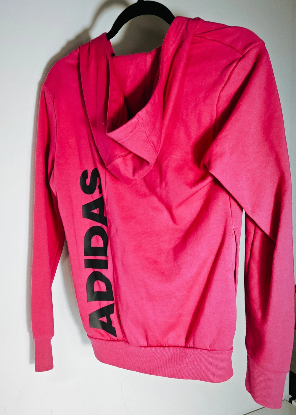 Chandail à capuchon rose fuchsia de Adidas avec le mot « ADIDAS » imprimé verticalement au dos.