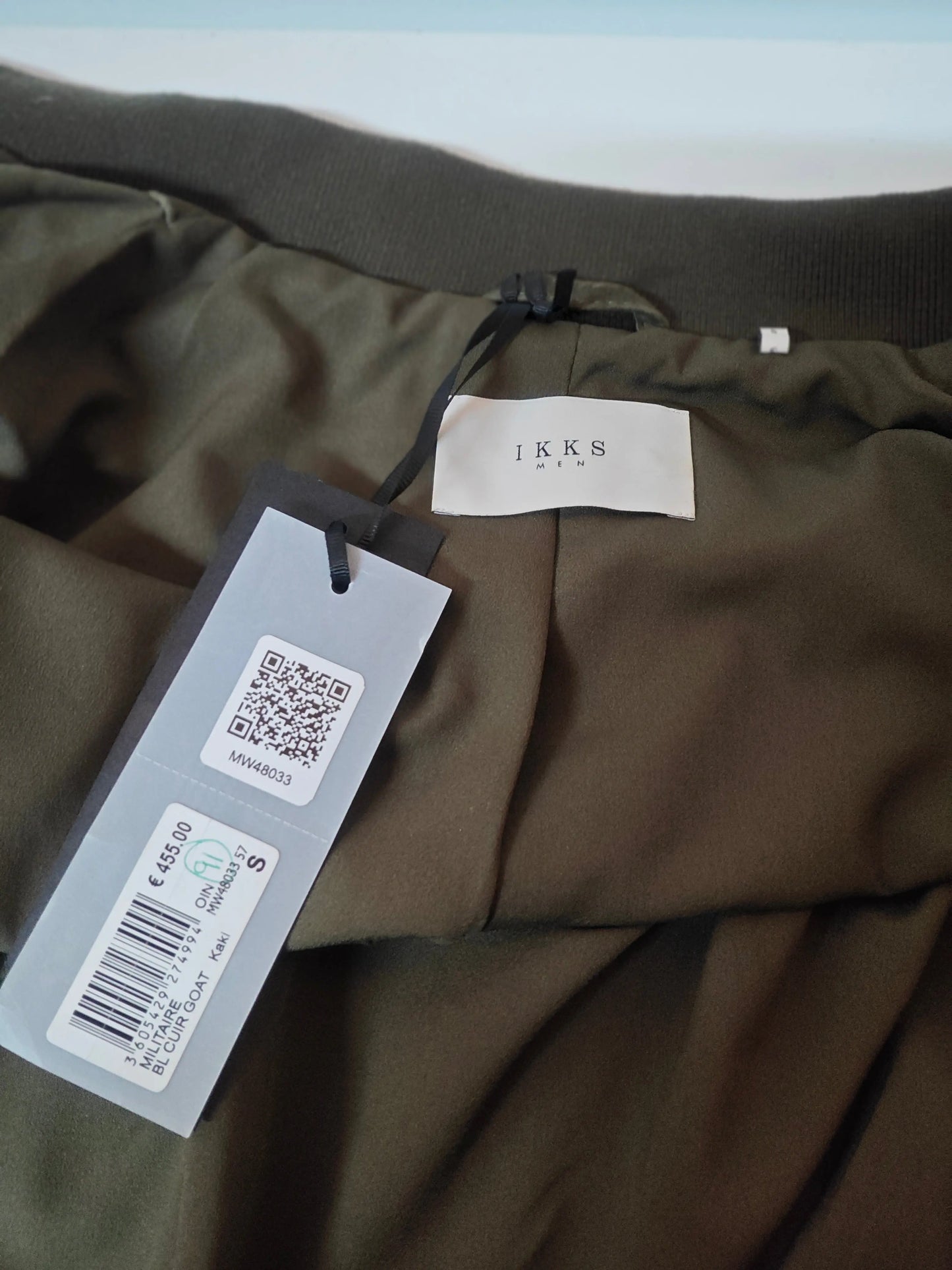 Blouson militaire en cuir kaki par IKKS, avec étiquette de prix et code QR apparents.