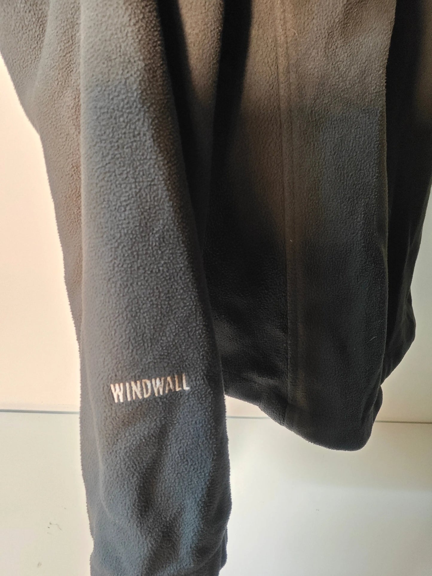 Polaire noire Windwall de The North Face, avec texture molletonnée et logo sur la manche.