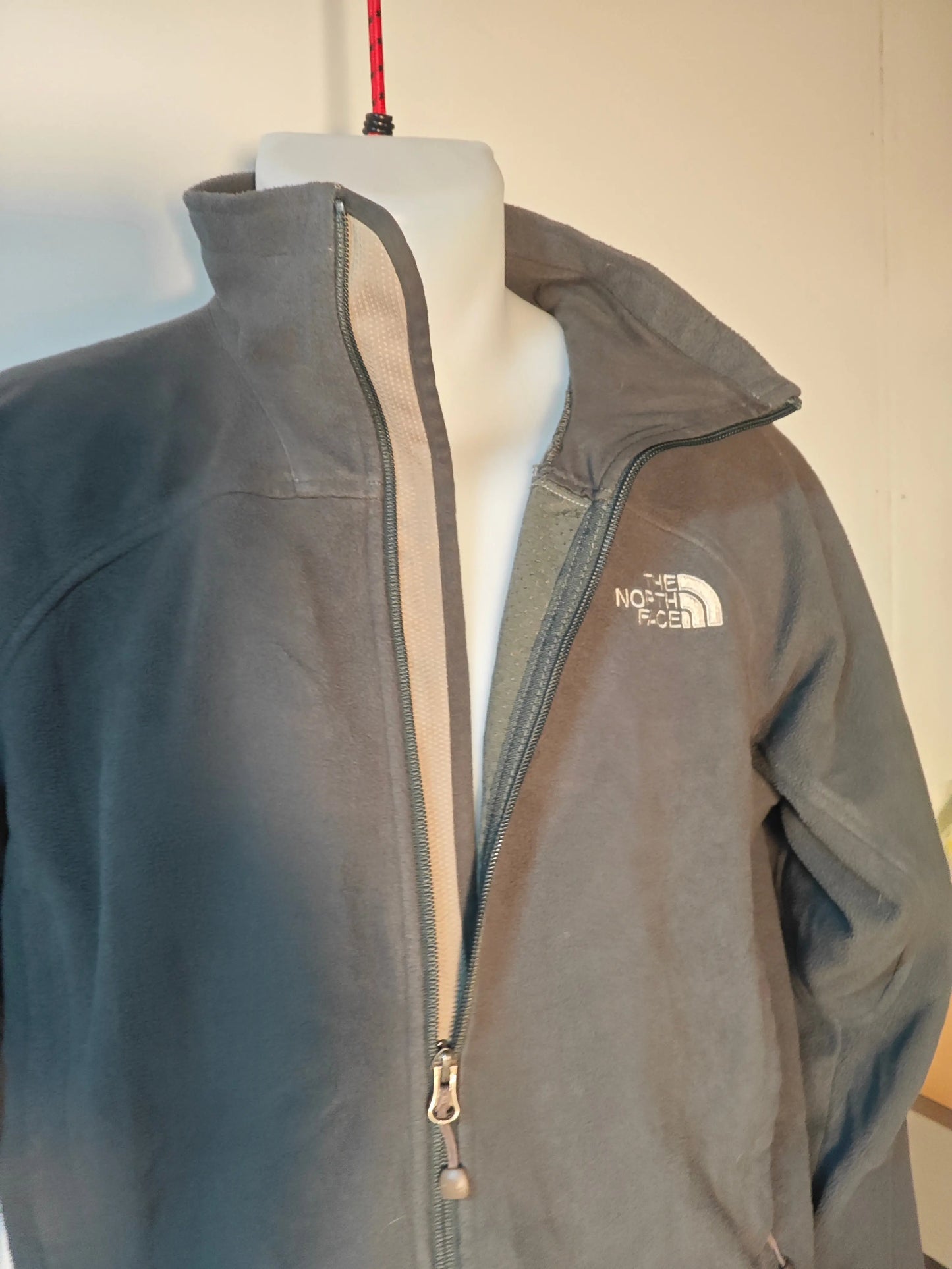Polaire grise The North Face avec fermeture éclair et logo sur la poitrine.