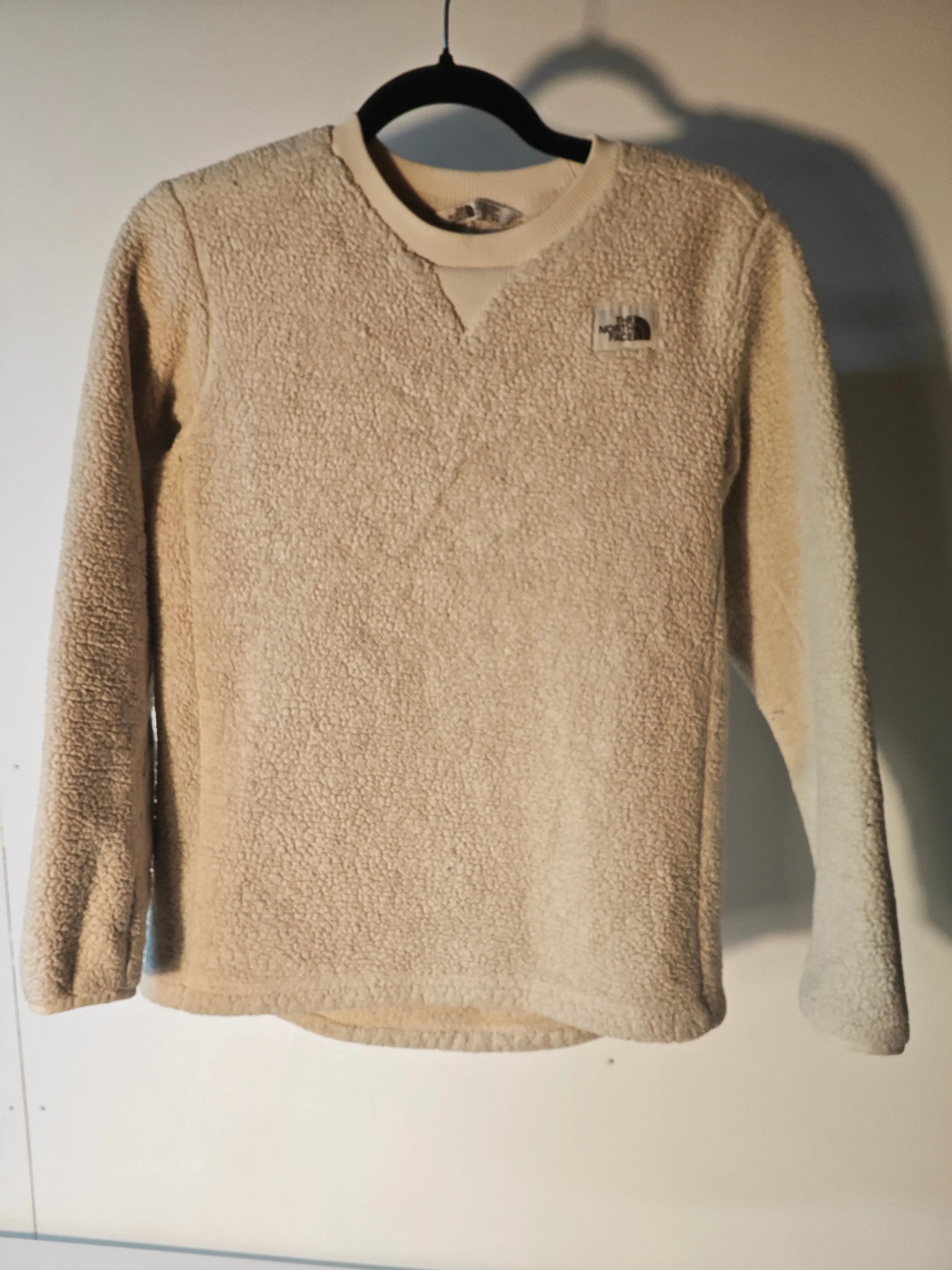 Pull en polaire sherpa beige de The North Face avec logo sur la poitrine.