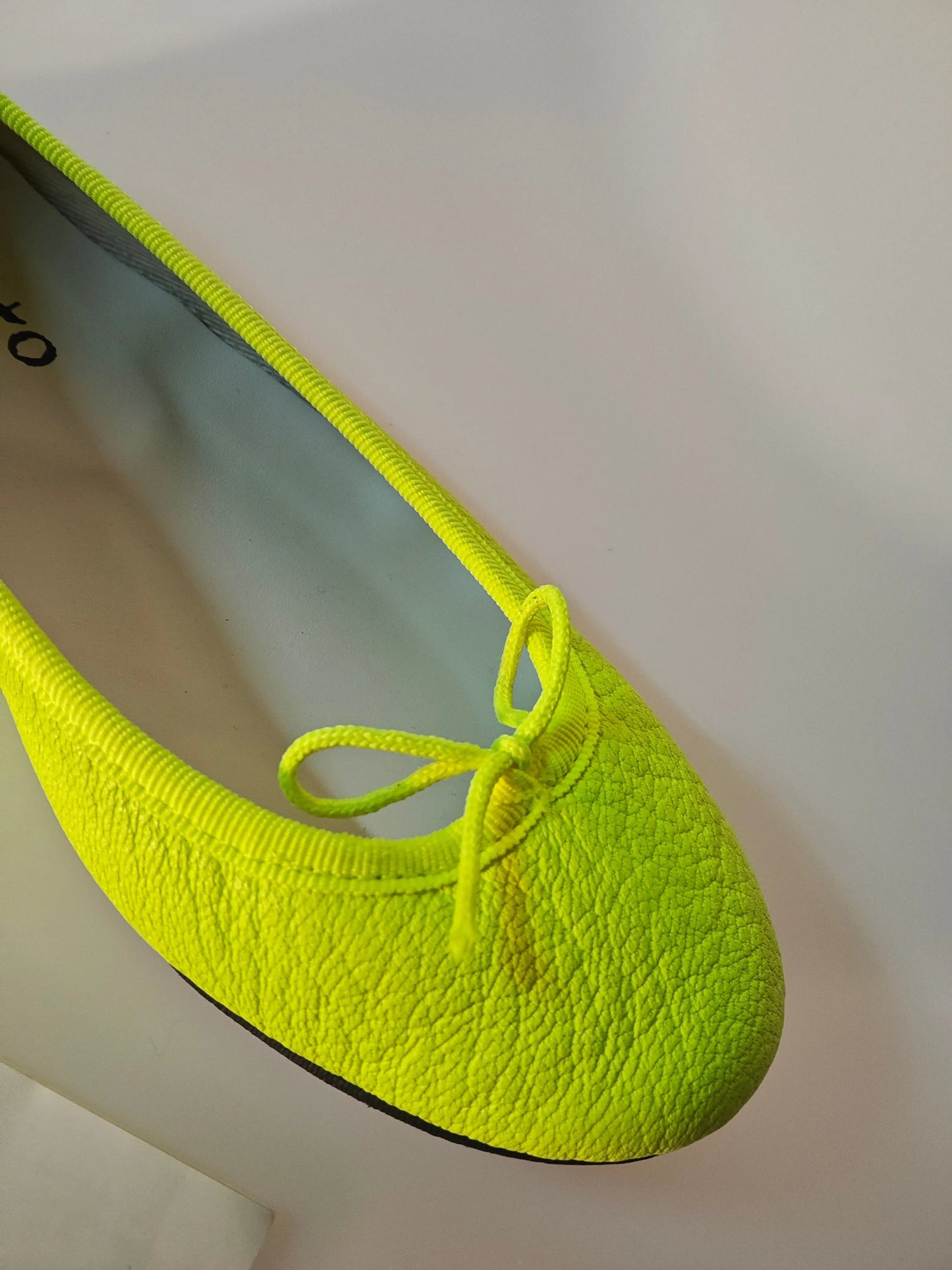 Ballerine en cuir vert vif de Repetto, avec un nœud décoratif sur le dessus et une semelle noire.