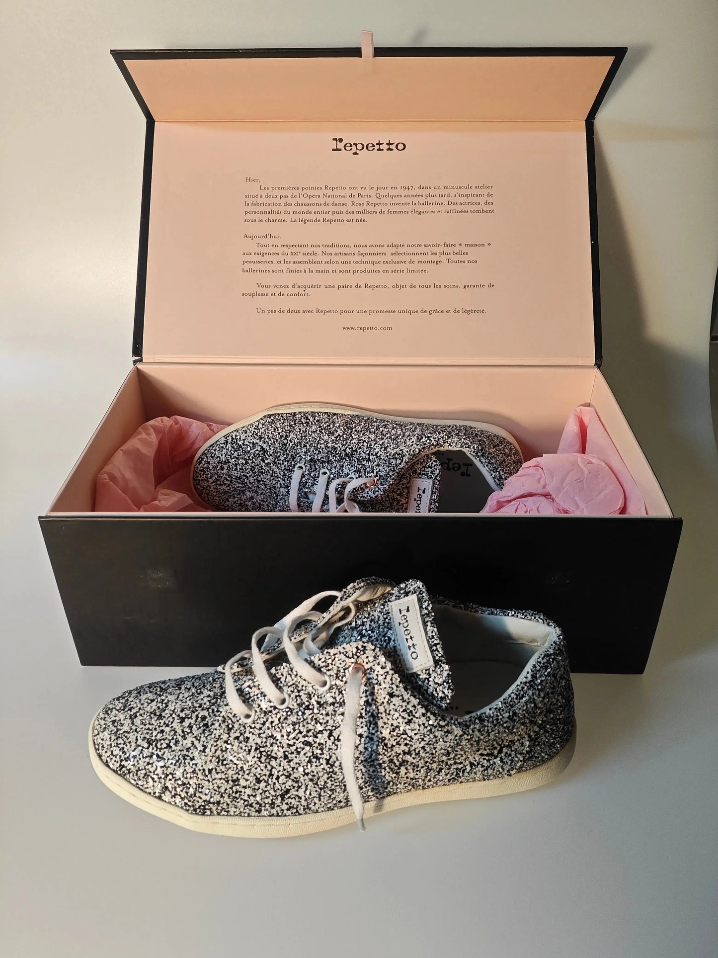 Baskets à lacets scintillantes de Repetto, présentées dans leur boîte noire avec papier de soie rose.