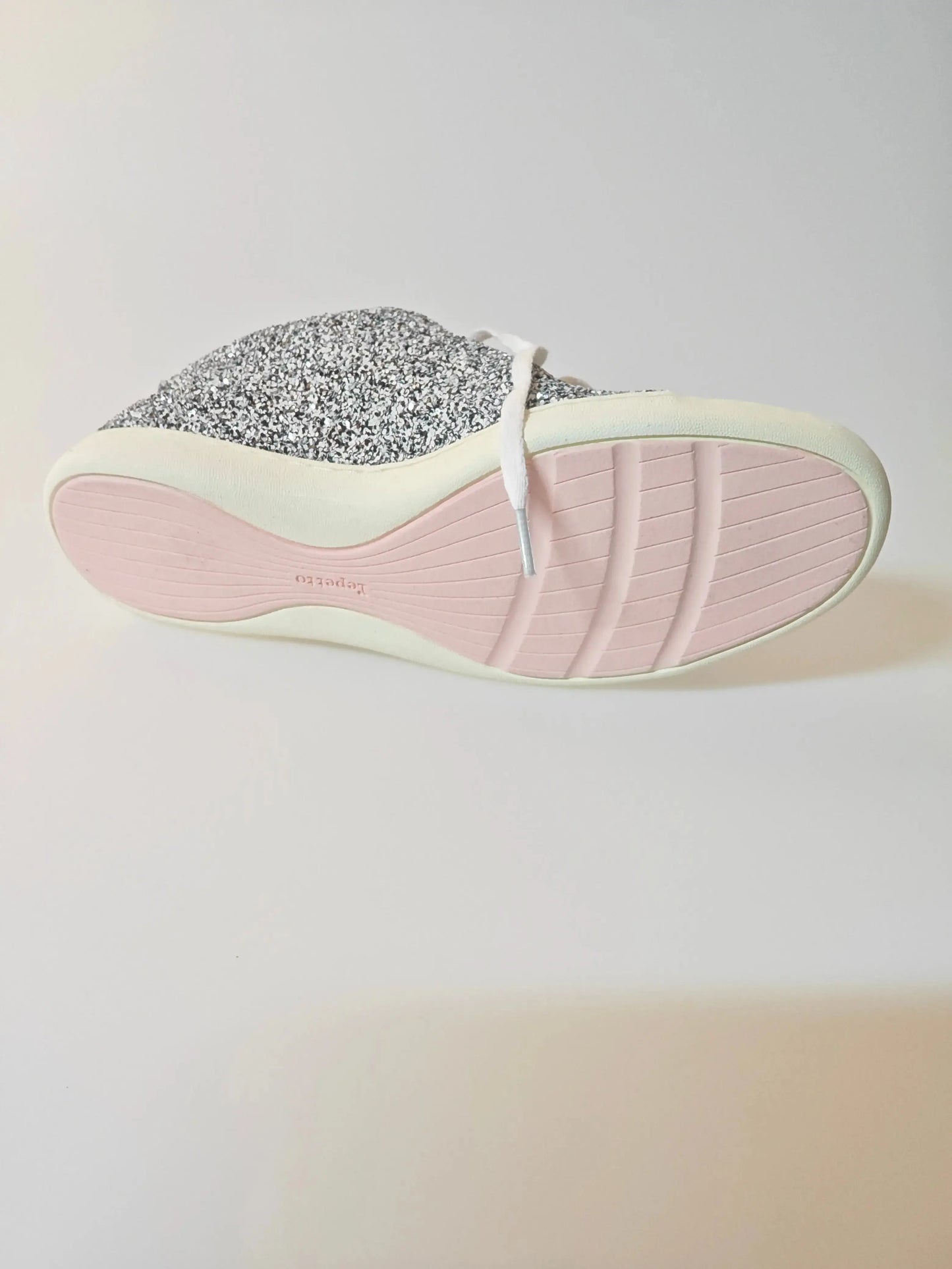 Sneaker à paillettes argentées de Repetto avec semelle rose et lacets blancs.