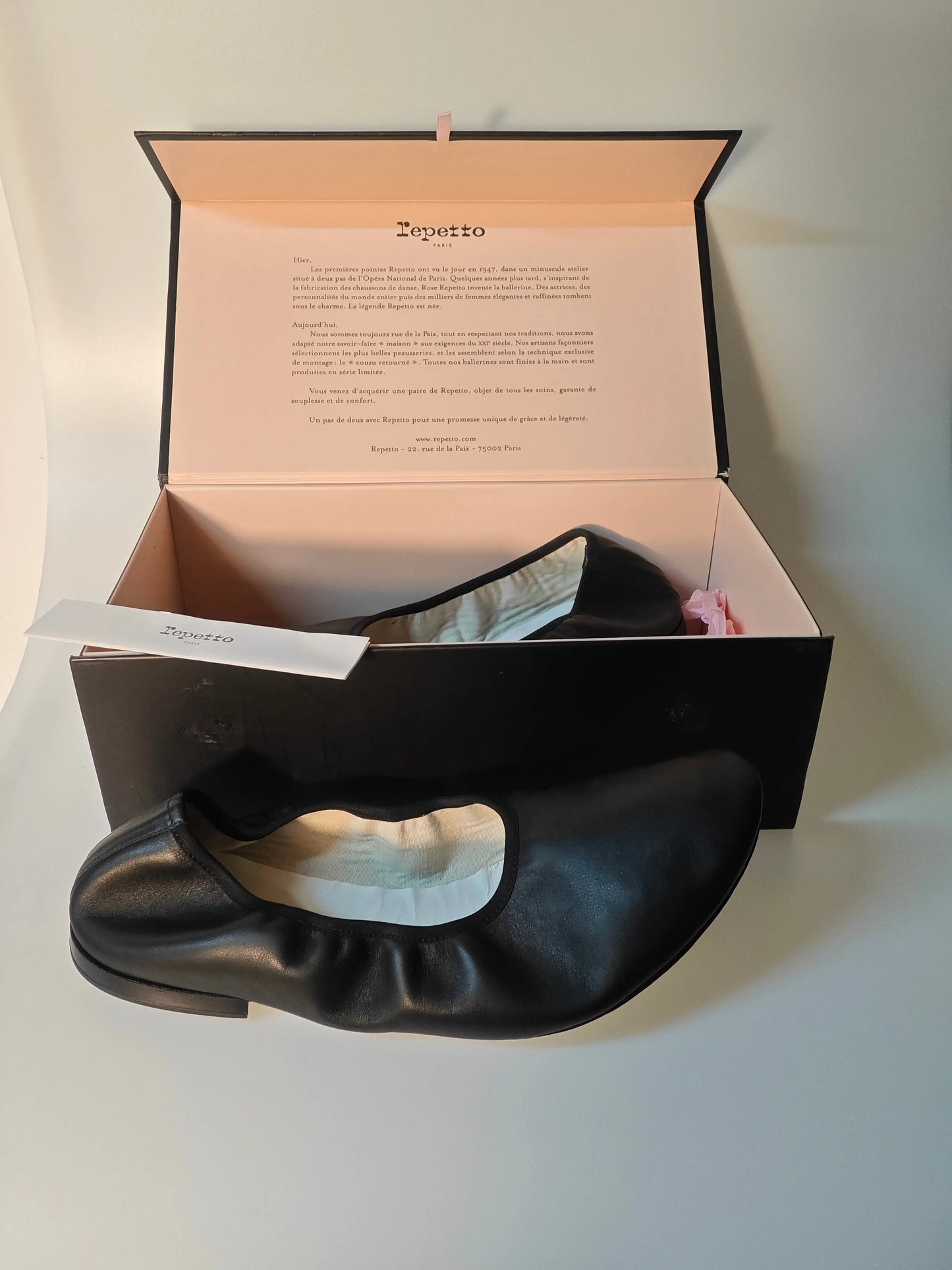 Ballerines noires en cuir de Repetto avec leur boîte, présentées à plat.