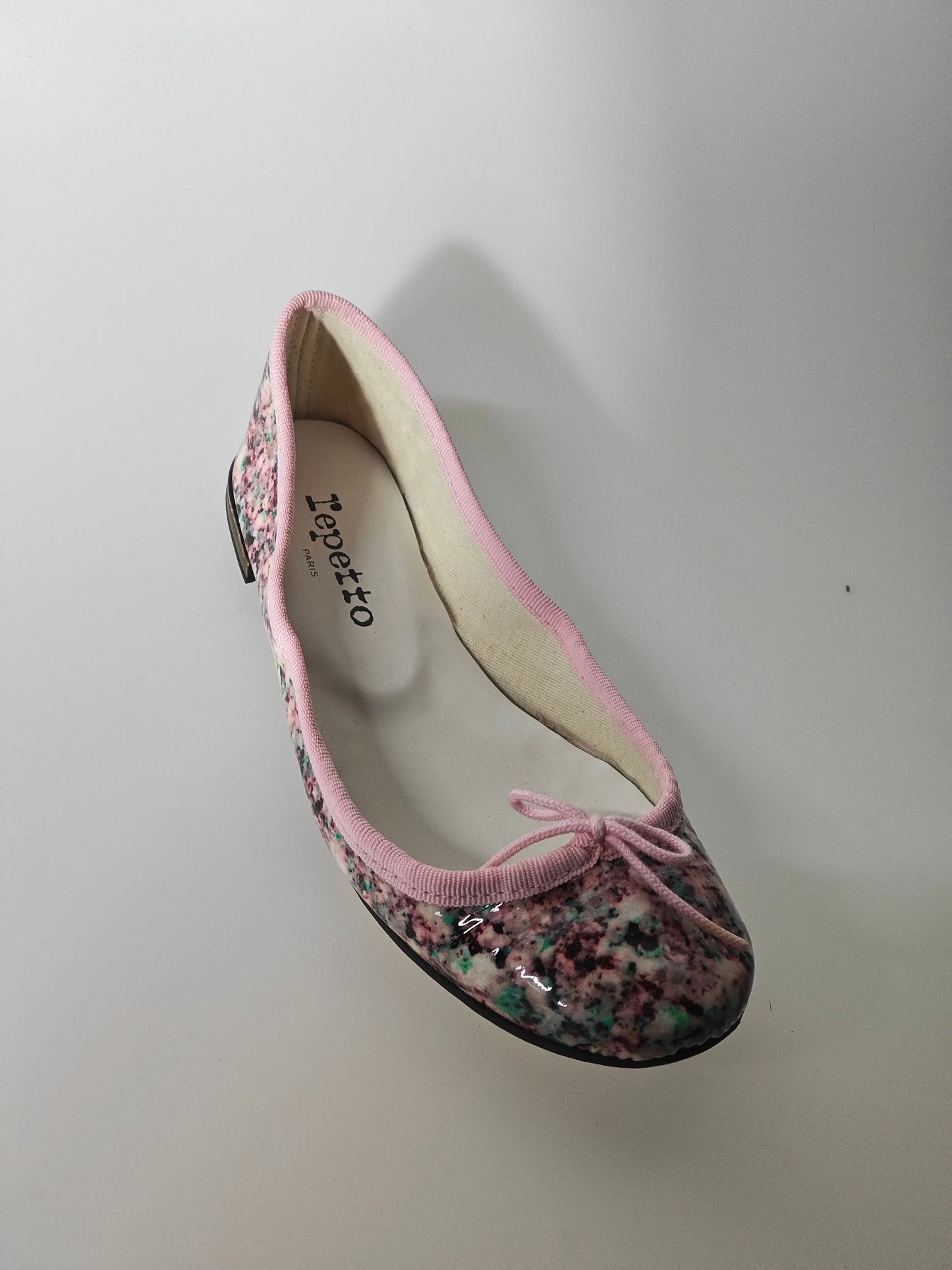Ballerine imprimée, par Repetto, avec bordure rose et petit nœud sur le dessus.