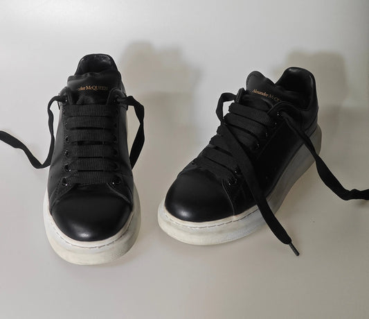 Chaussures en cuir noires Alexander McQueen, lacets noirs et semelles blanches épaisses.