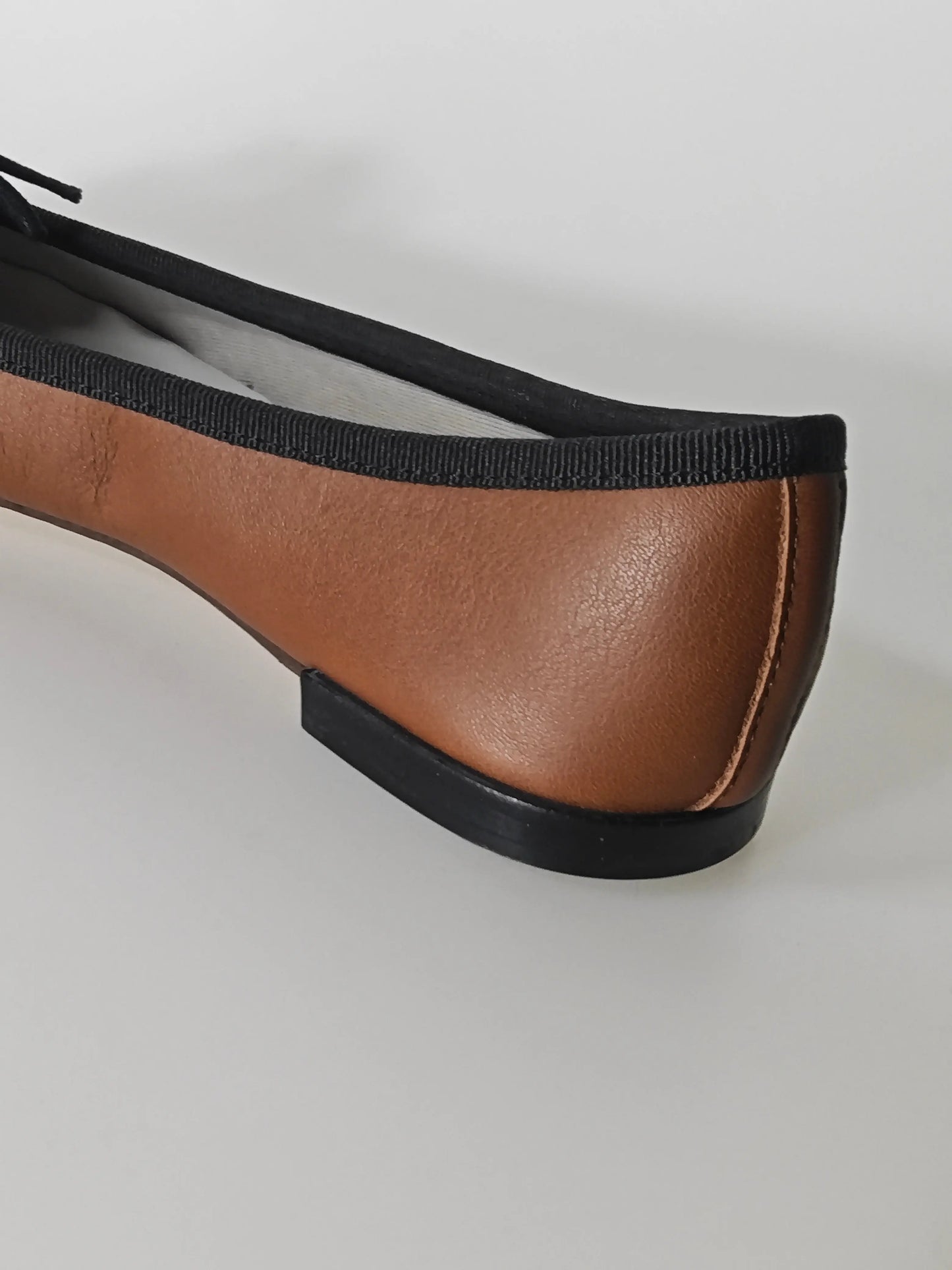 Ballerine marron en cuir de Repetto, avec une bordure noire et semelle plate.