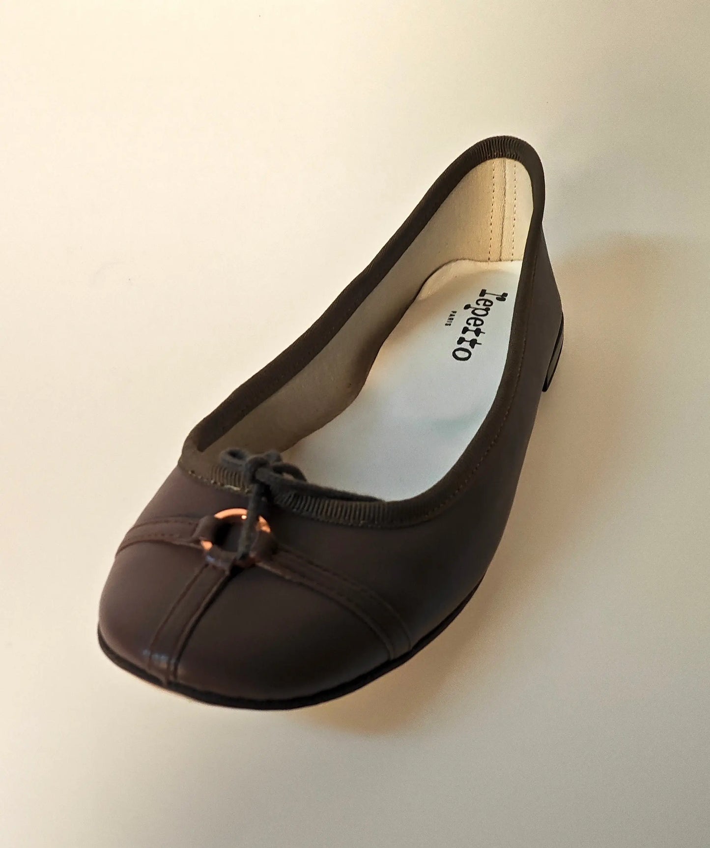 Ballerine marron en cuir, de Repetto, avec un nœud décoratif et des finitions ton sur ton.