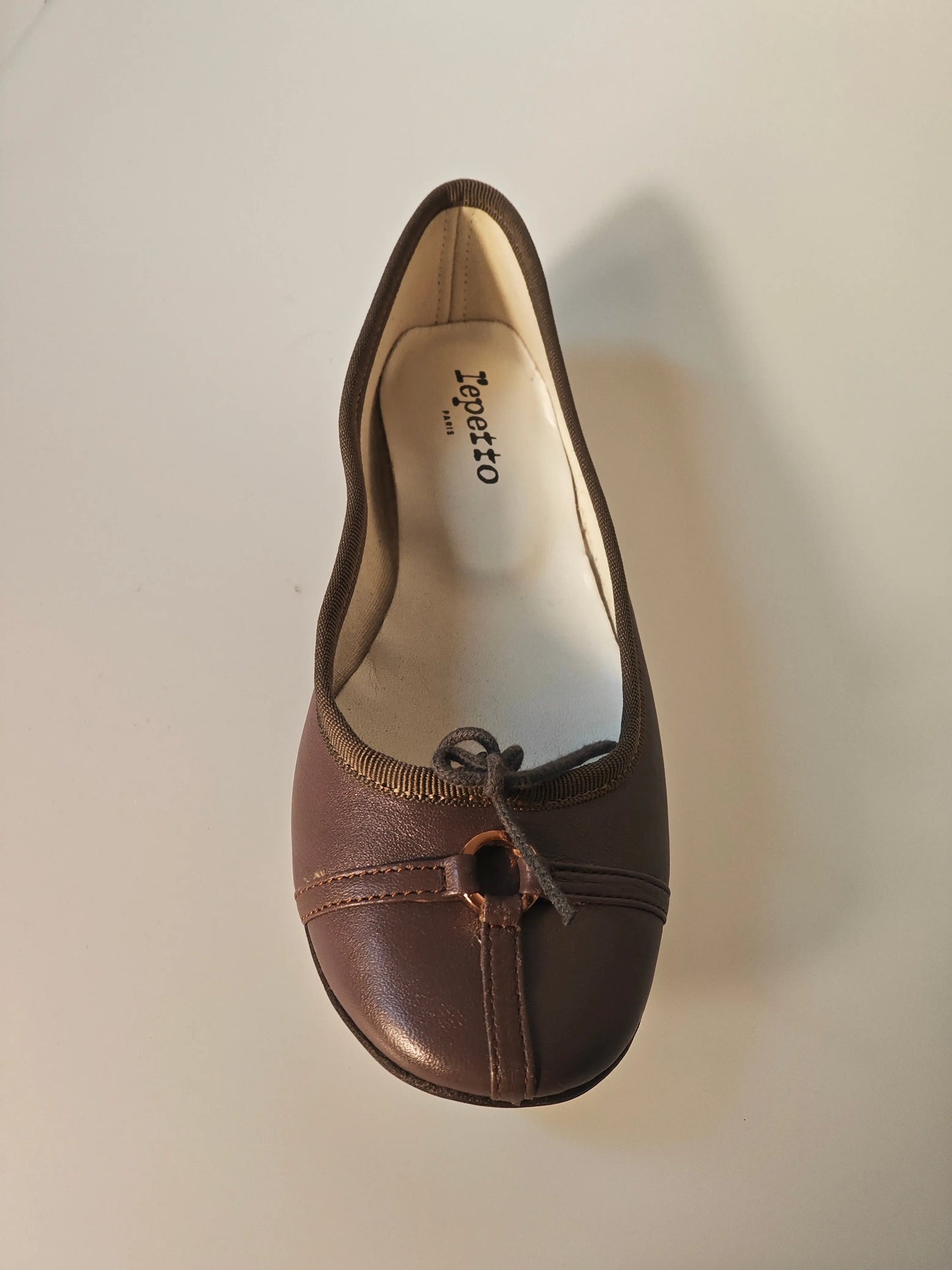 Ballerine marron en cuir de Repetto, avec un nœud décoratif et des surpiqûres discrètes.