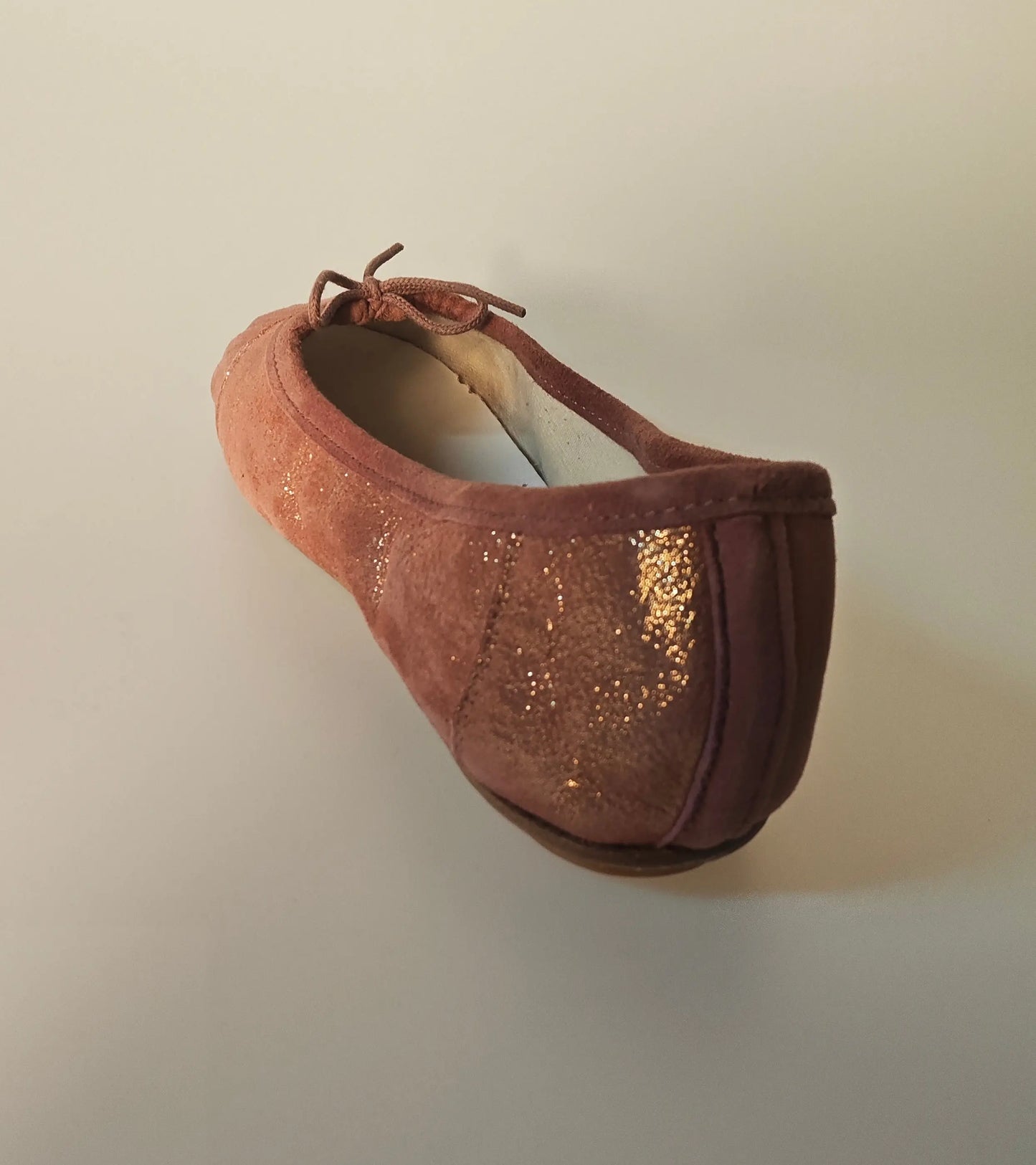 Ballerine rose poudré de Repetto, avec des paillettes dorées brillantes et un petit nœud décoratif.