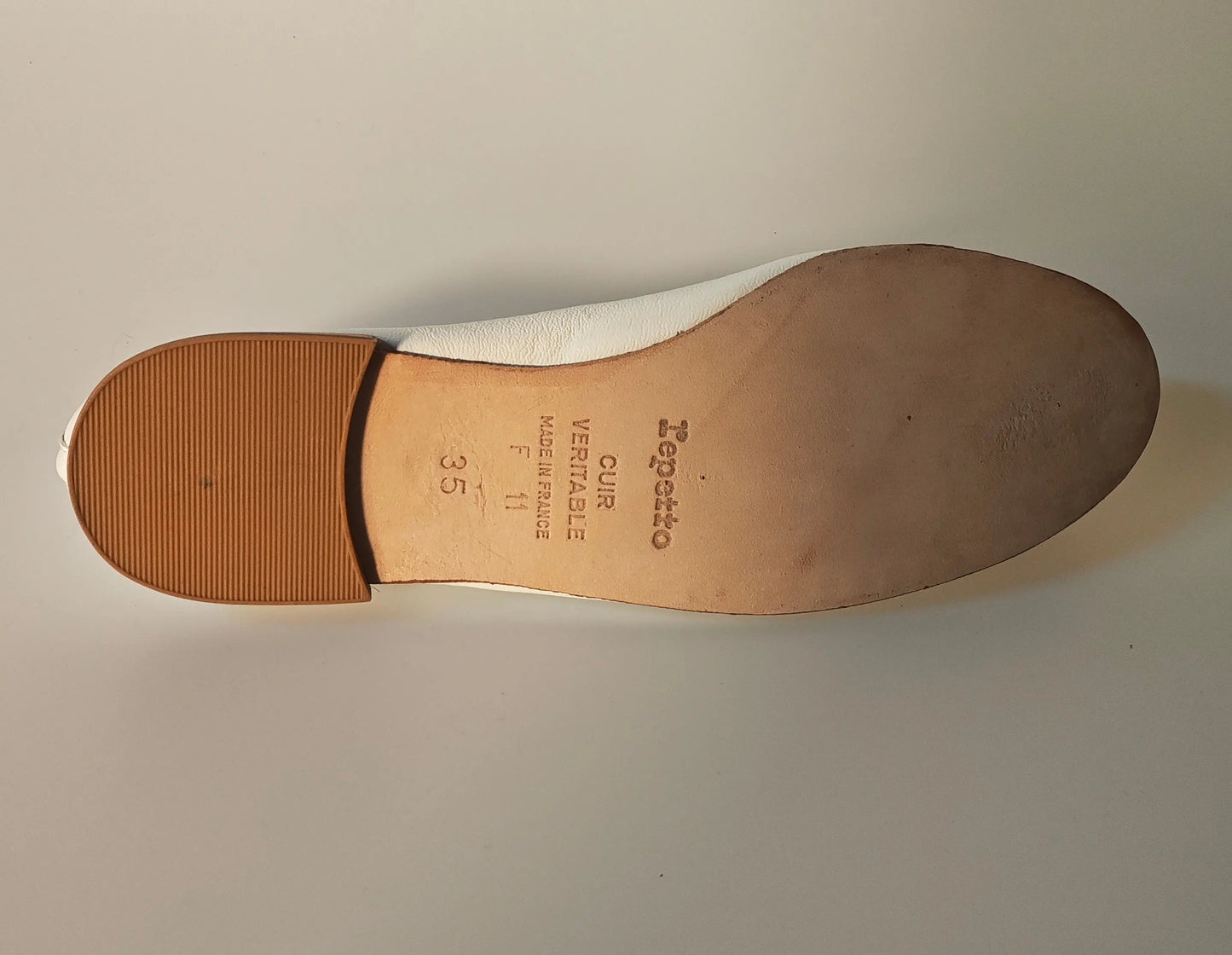 Ballerine blanche en cuir véritable de Repetto, montrant la semelle marron avec le logo imprimé et la taille.