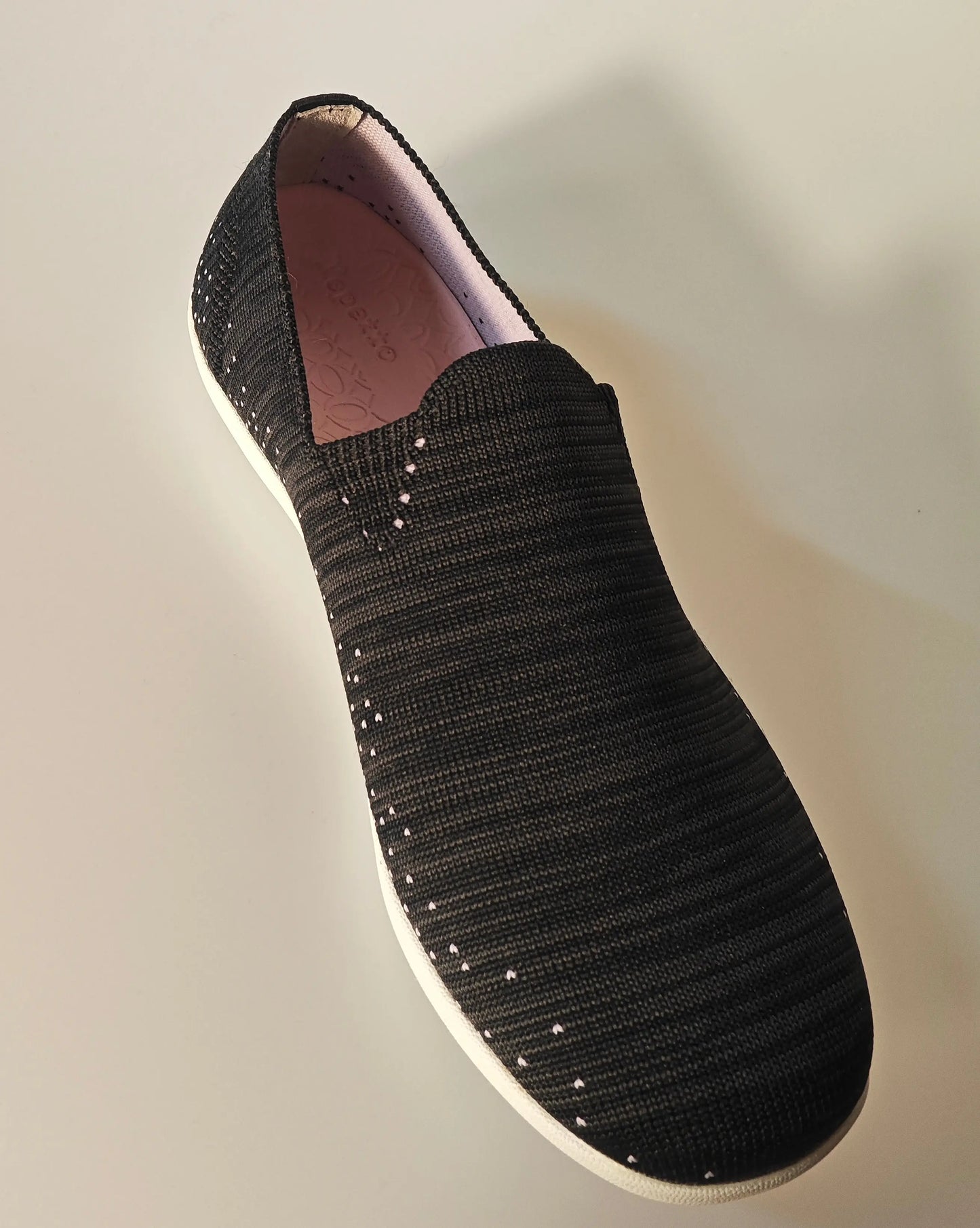 Chaussure de course noire en maille par Repetto, avec de petites ponctuations roses et une semelle blanche.