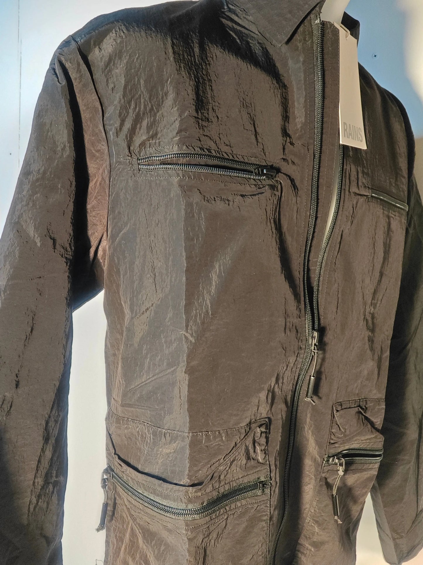 Veste noire imperméable de Rains avec fermeture éclair et poches zippées.