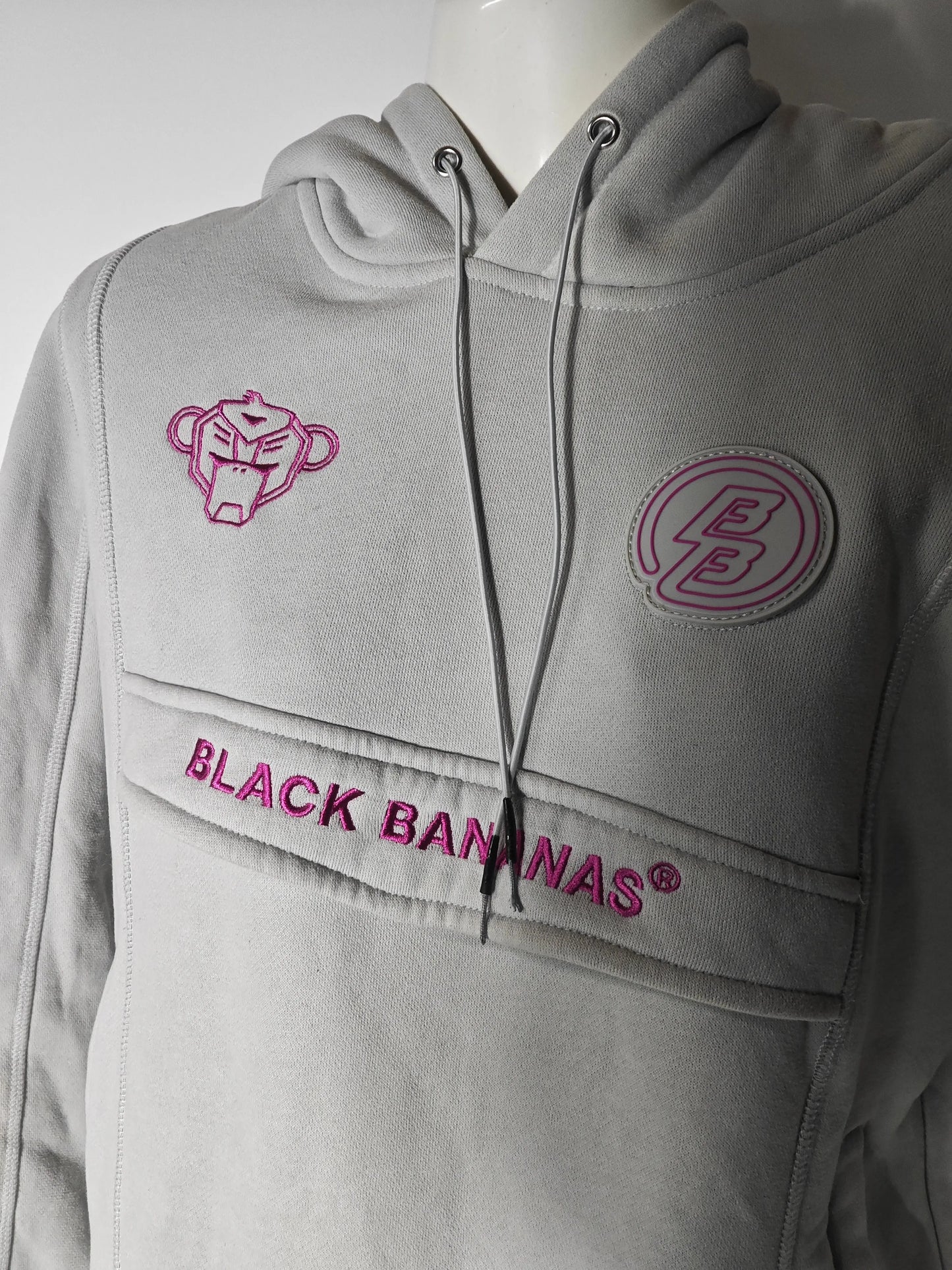 Hoodie gris clair de Black Bananas® avec logo rose et détails décoratifs, présenté sur un mannequin.