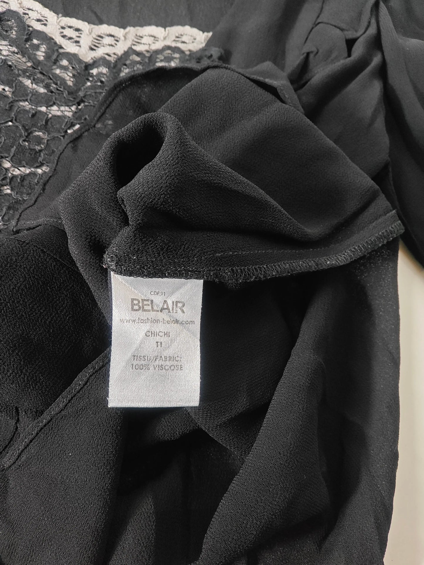 Blouse noire en viscose Belair, avec détails en dentelle blanche et volants.