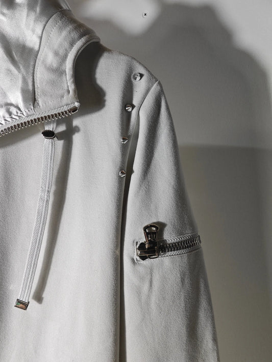Veste à capuche blanche de Joey Martin’s Paris avec détails cloutés et fermeture éclair sur la manche.