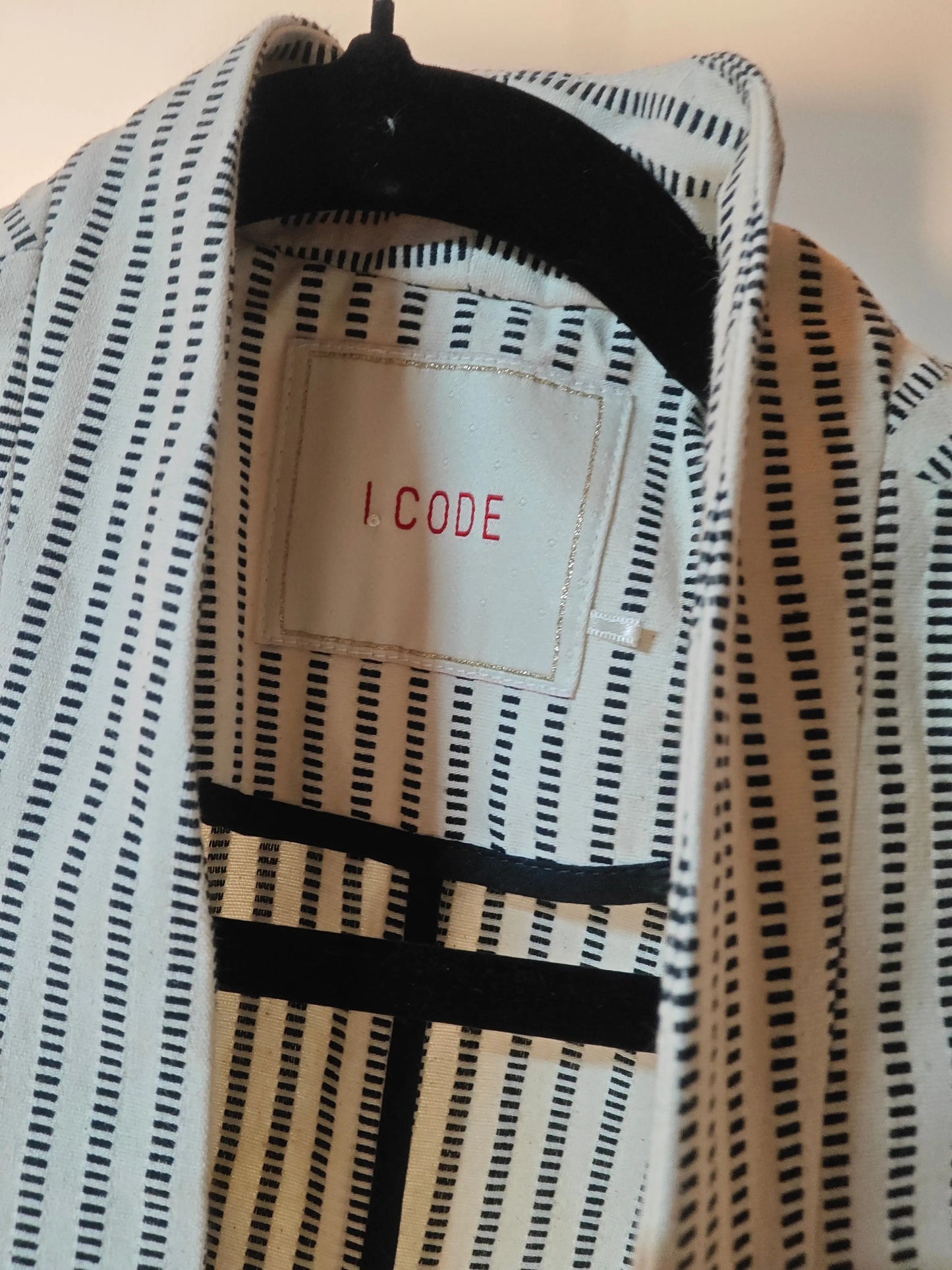 Veste rayée écru et noire, de I.CODE by IKKS, avec motif à rayures verticales et doublure noire.