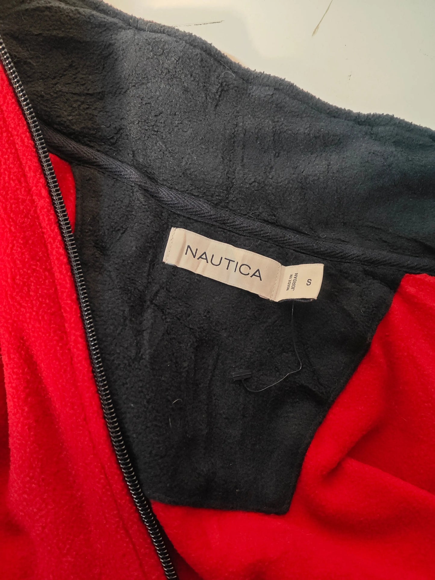 Veste polaire rouge et noire par Nautica, taille S avec étiquette de la marque visible.