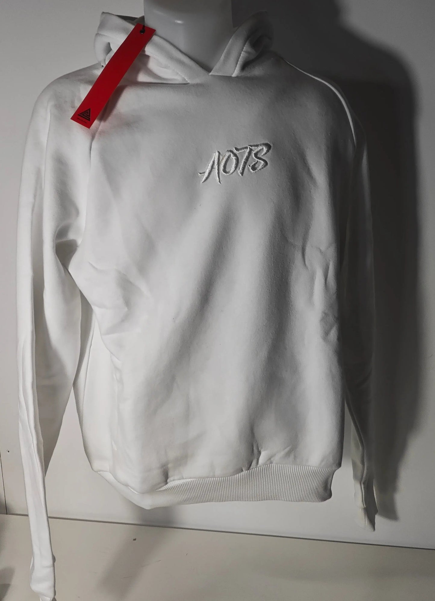 Sweat à capuche blanc de AOTS, avec broderie décorative sur le devant et étiquette rouge sur la capuche.