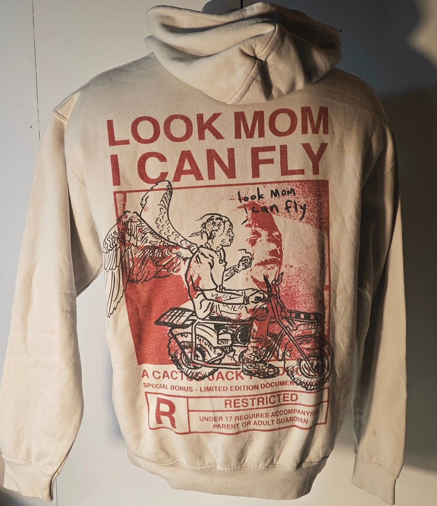 Sweat à capuche écru de Travis Scott, avec motif graphique « Look Mom I Can Fly » imprimé au dos.