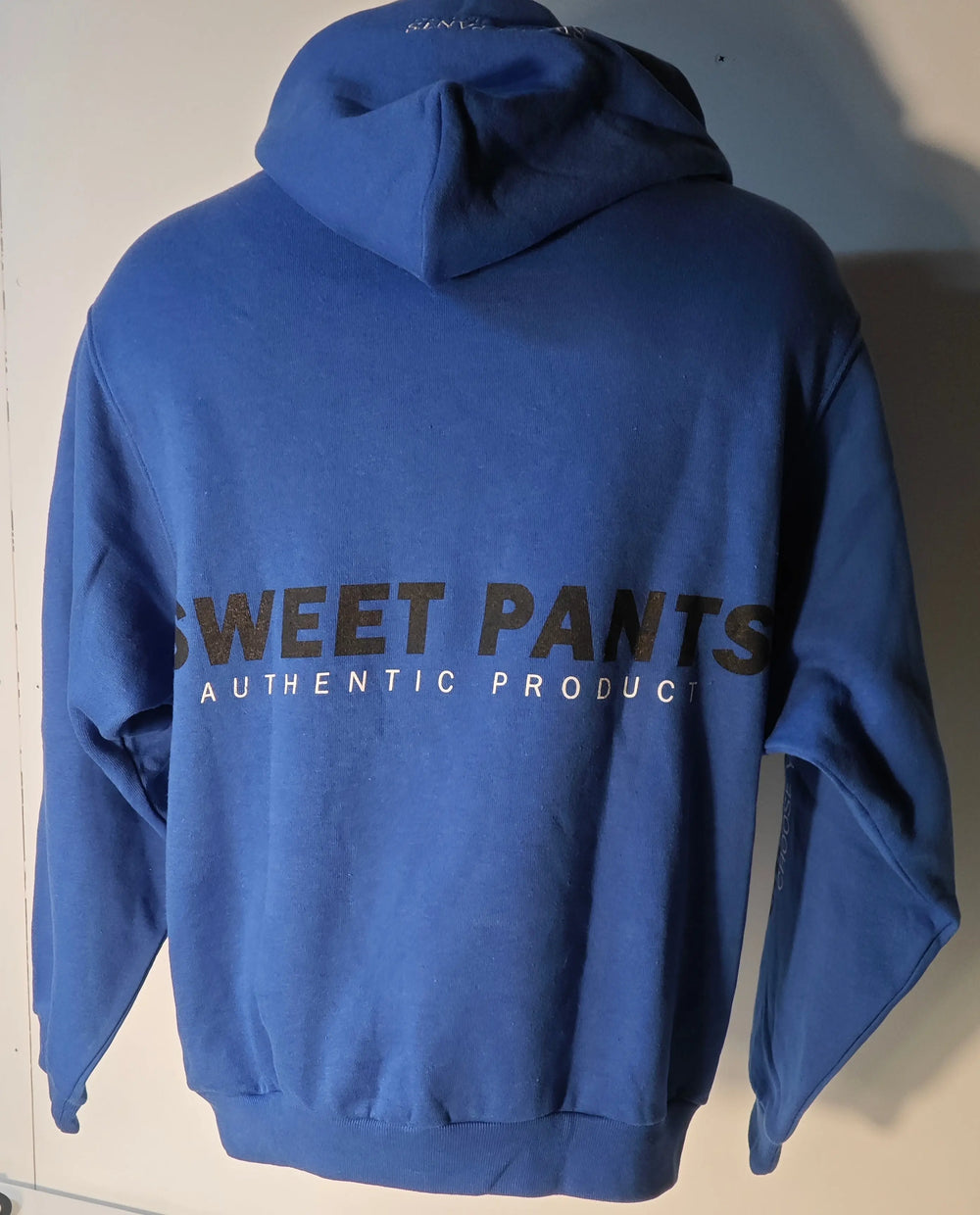 Sweat à capuche oversize bleu de Sweet Pants, avec inscription "SWEET PANTS AUTHENTIC PRODUCT" au dos.