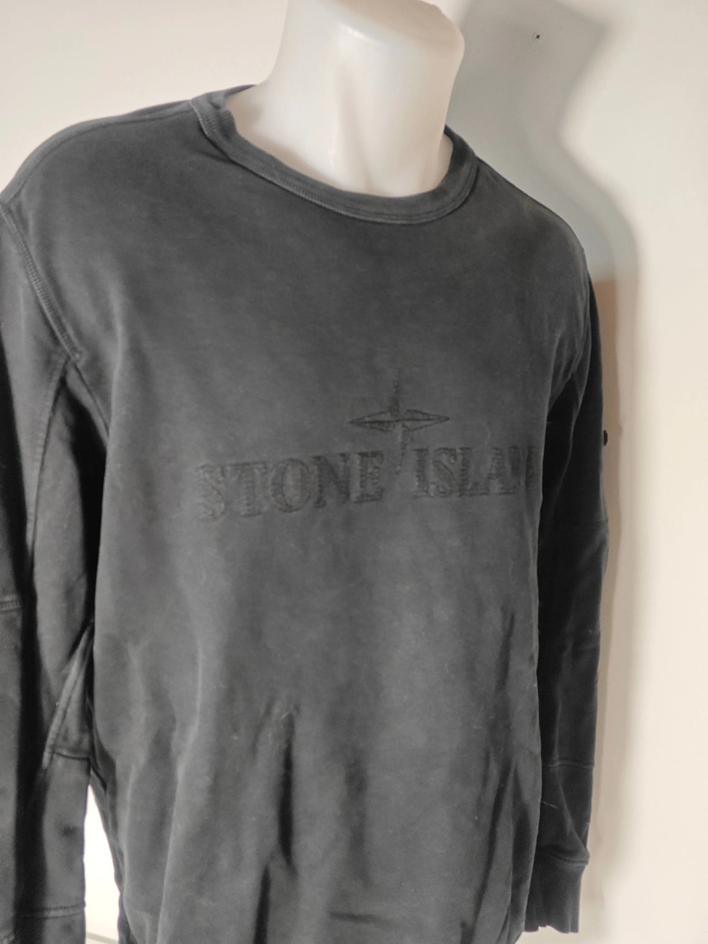 Sweat noir brodé ton-sur-ton de Stone Island, présenté sur un mannequin buste blanc et col rond.