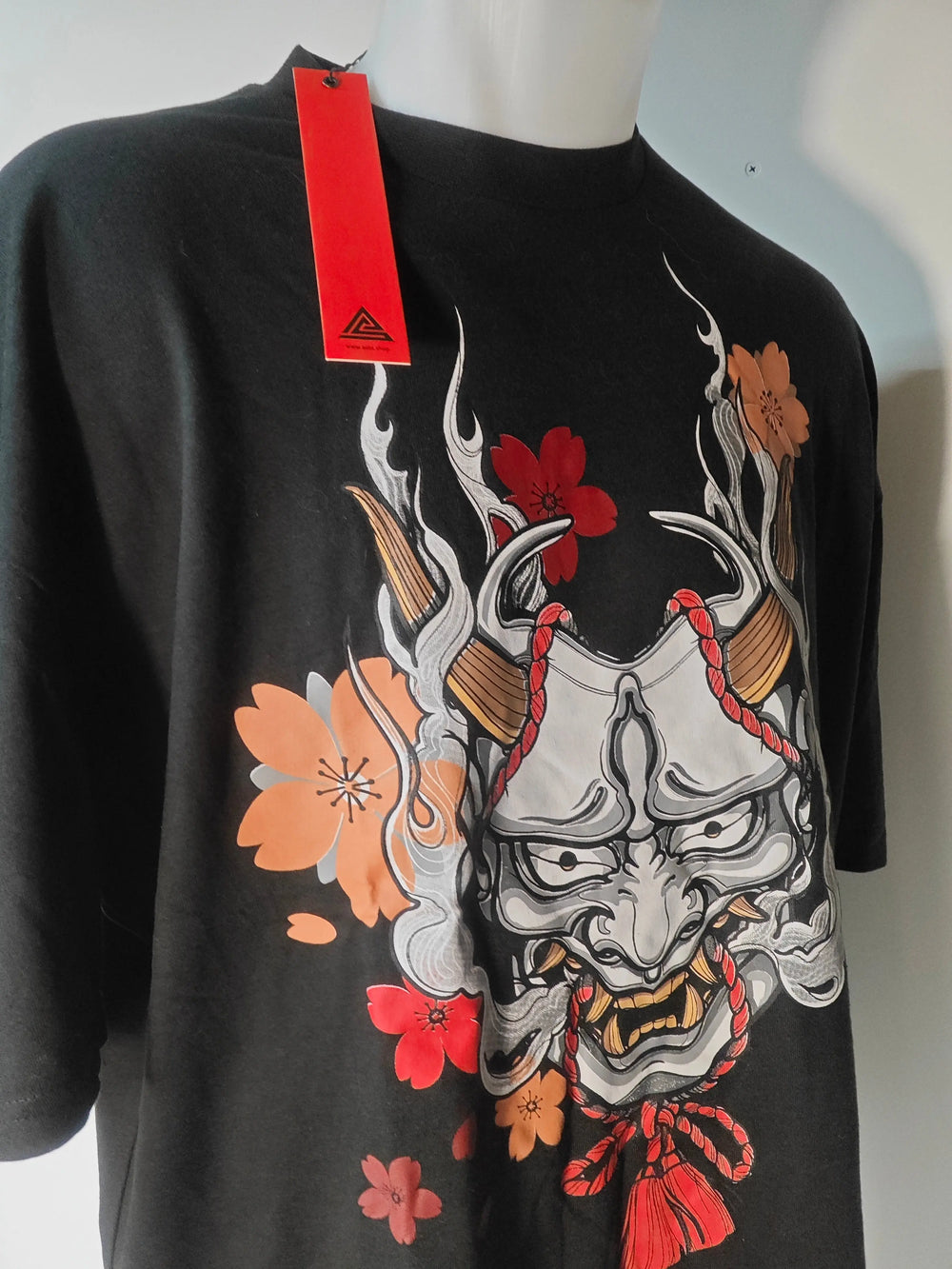 T-shirt noir Art of the Streets, avec un masque japonais orné de fleurs rouges et orange.