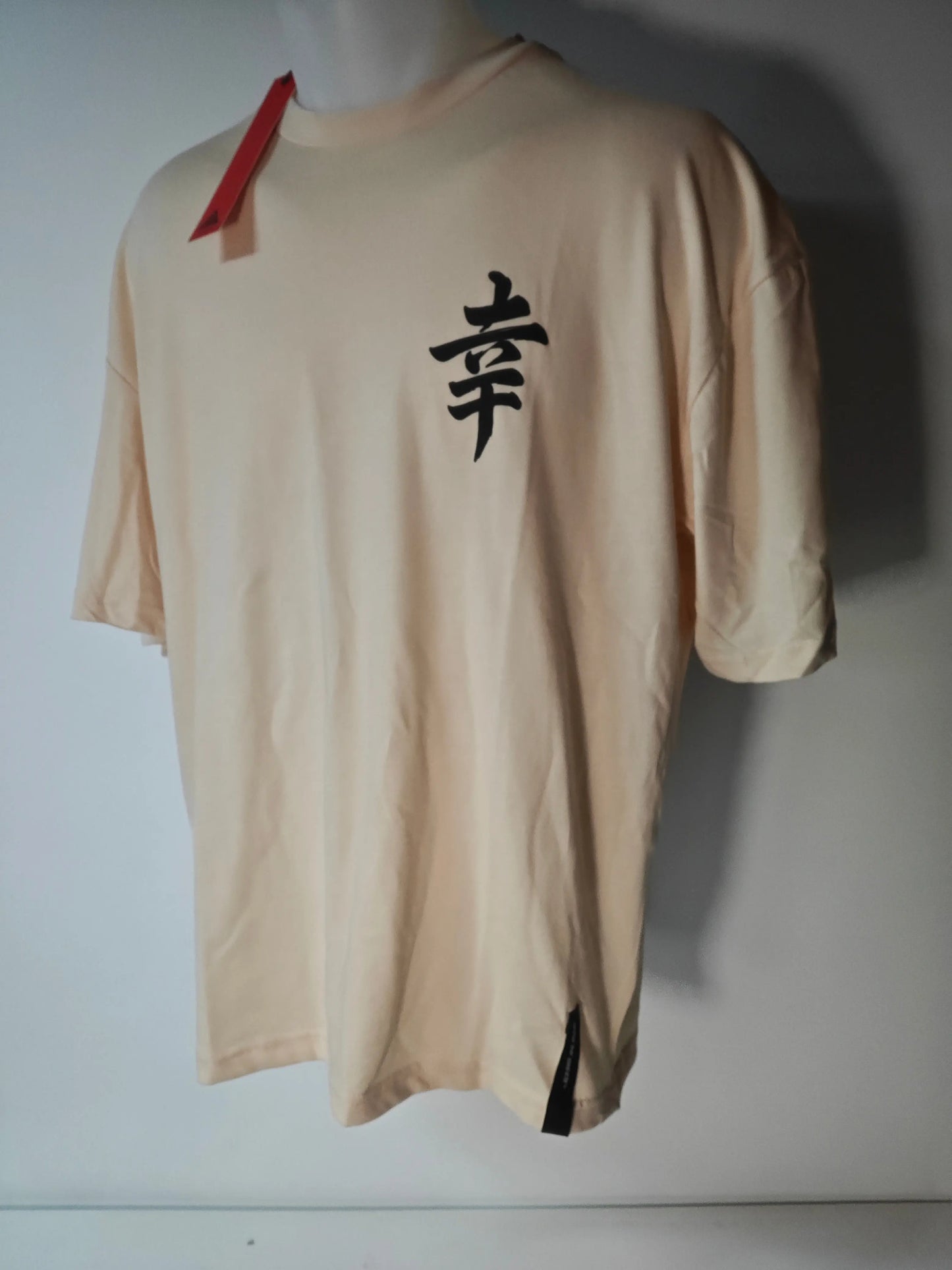T-shirt beige AOTS Art Of The Streets avec un kanji noir imprimé sur le devant et une étiquette rouge au col.