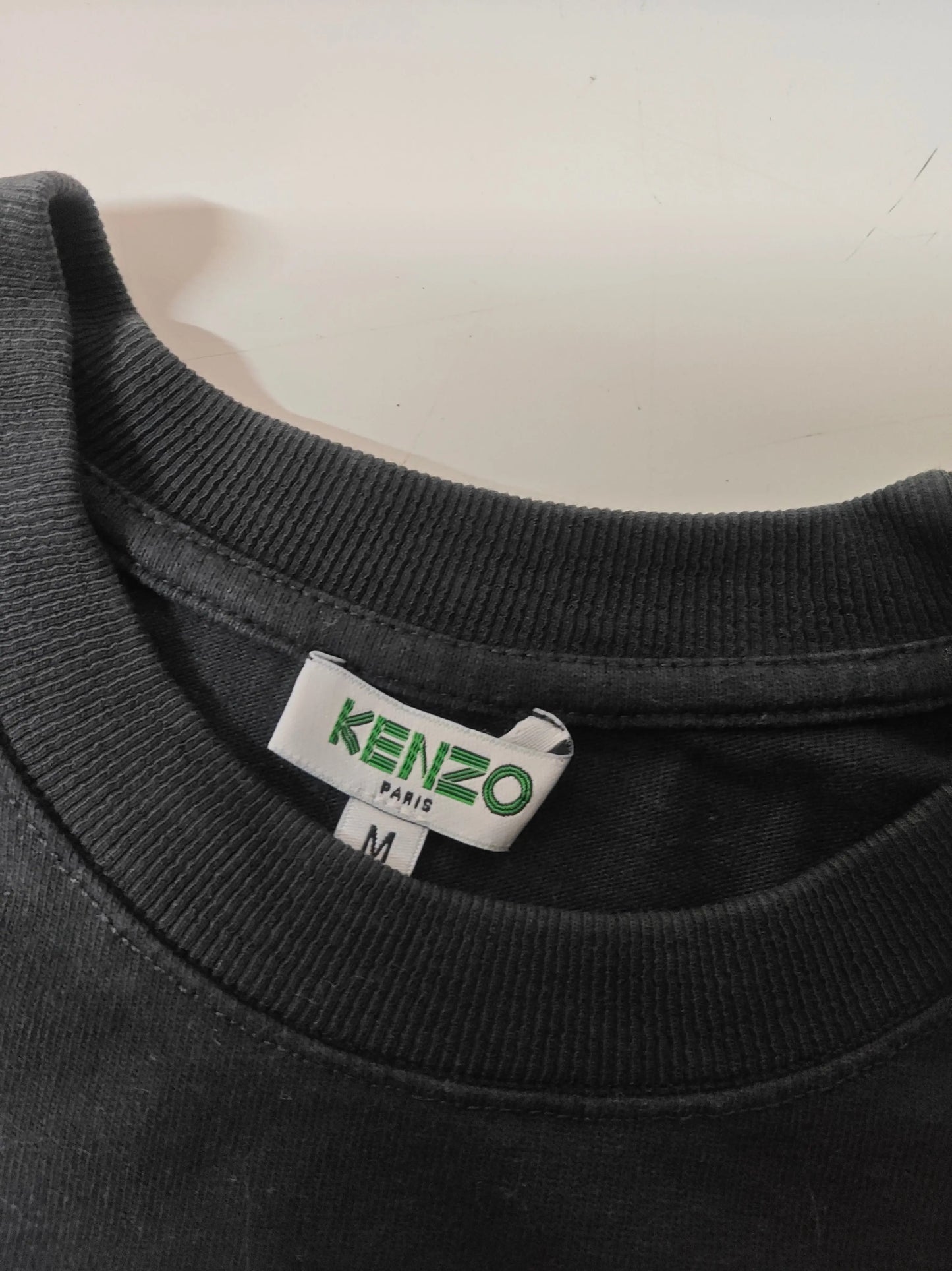 T-shirt noir de taille M par Kenzo, avec col rond côtelé et étiquette de la marque visible.