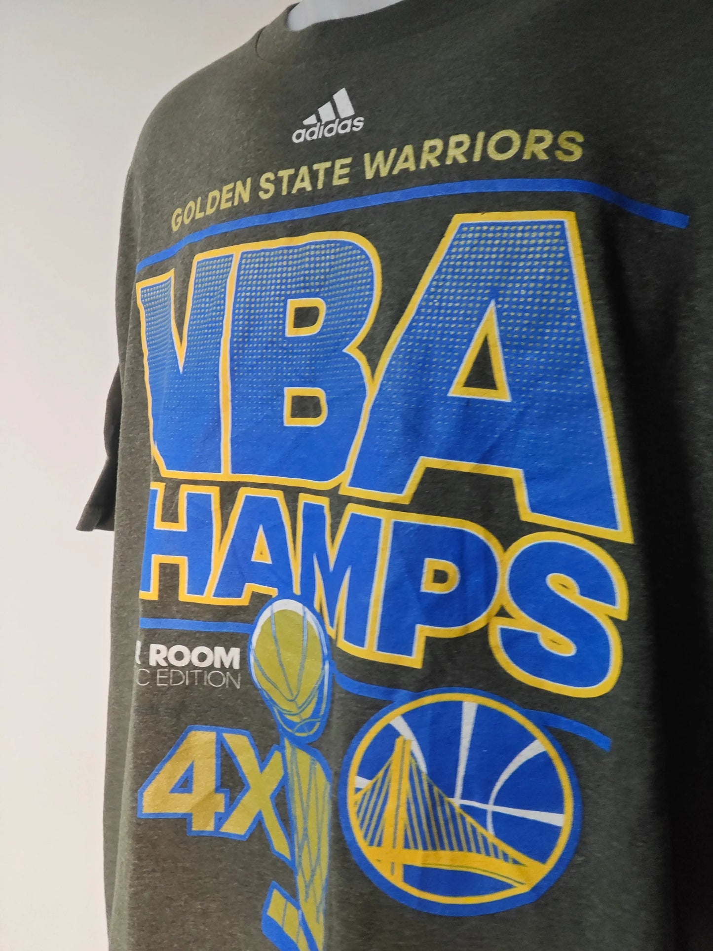 T-shirt gris de Golden State Warriors par Adidas, avec imprimé NBA Champs 2015 et logo de l'équipe.