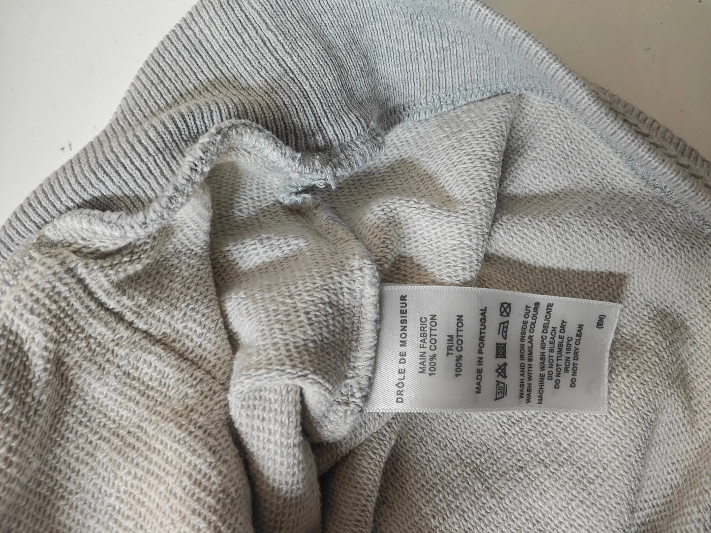 Sweat à capuche gris chiné de Drôle de Monsieur, montrant l'étiquette avec les instructions de lavage.