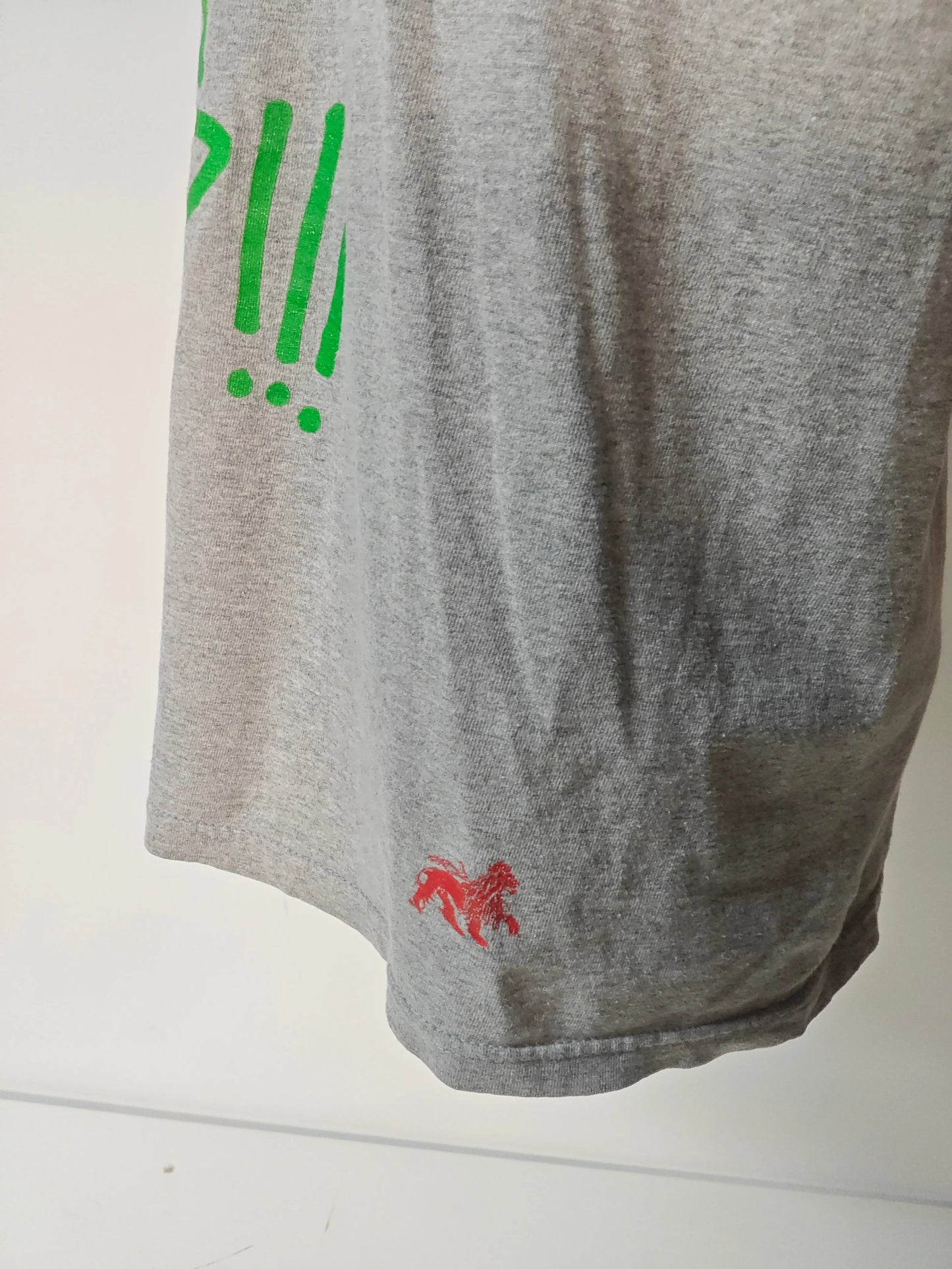 T-shirt gris de Stüssy, avec un imprimé graphique vert et un logo rouge en bas, en coton, en seconde main.