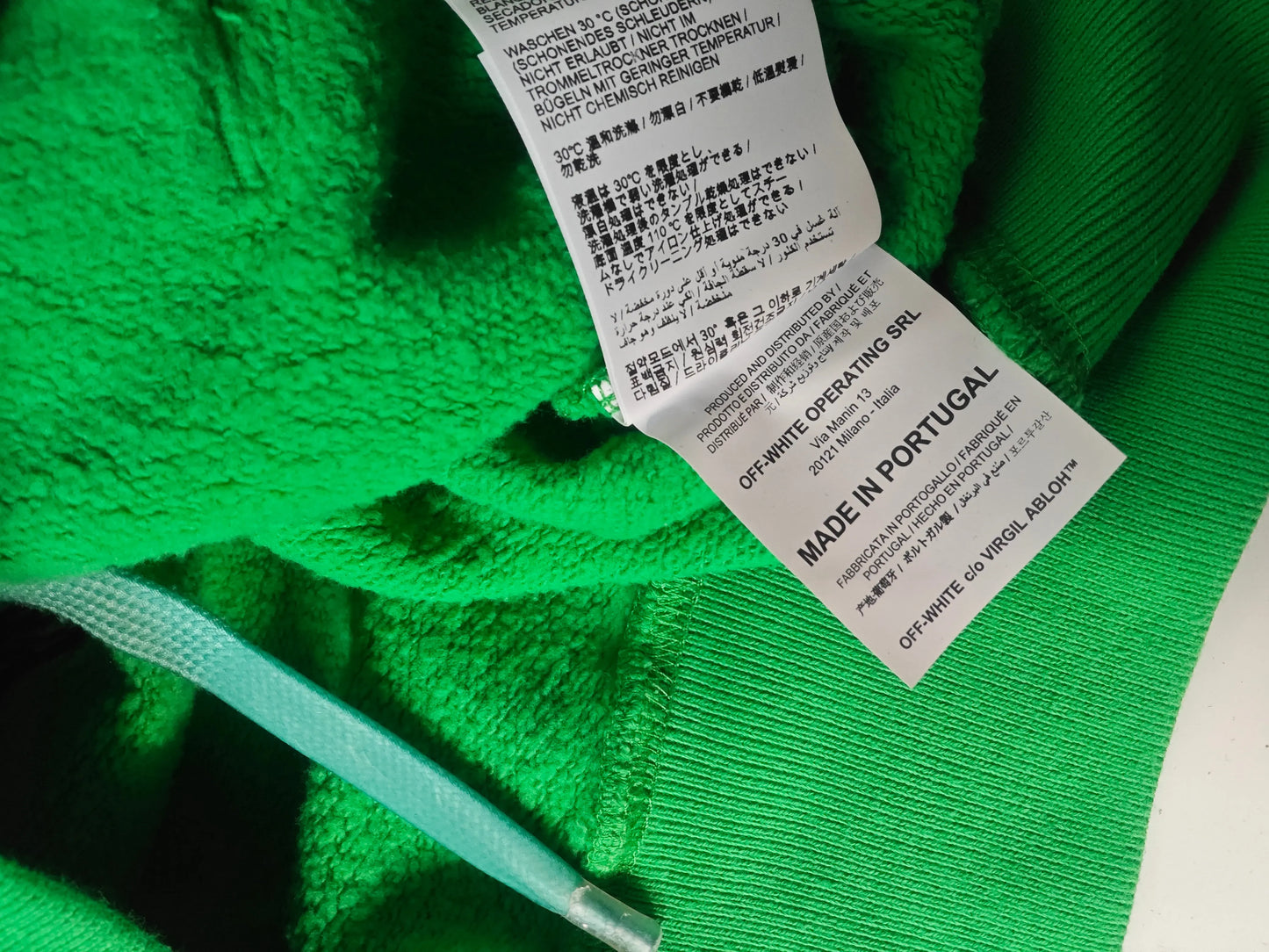 Sweat à capuche vert par Off-White, étiquette d'entretien visible et cordon de serrage turquoise.