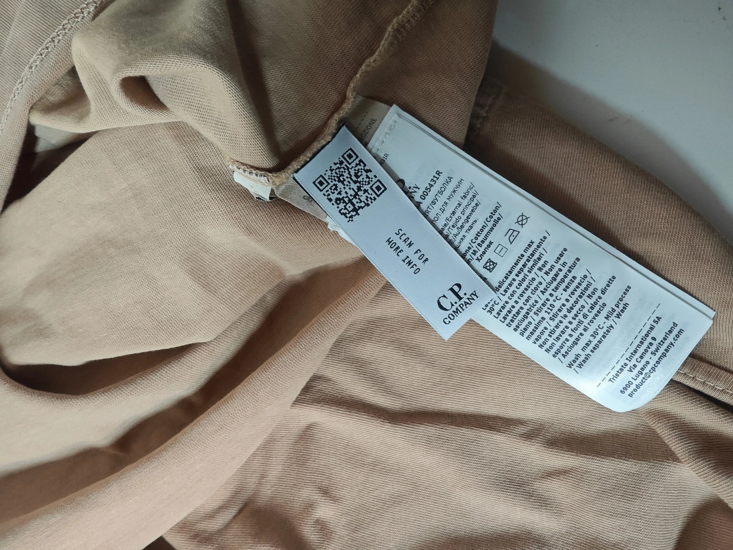 T-shirt couleur coquille de pâtisserie par C.P. Company, montrant l'étiquette de lavage.