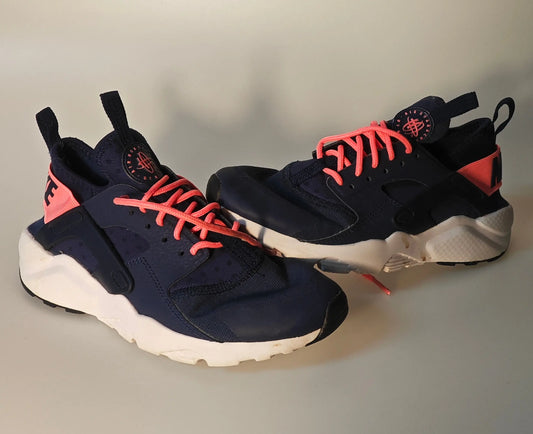 Paire de baskets bleu marine et rose par Nike, avec lacets rose vif et semelle blanche.