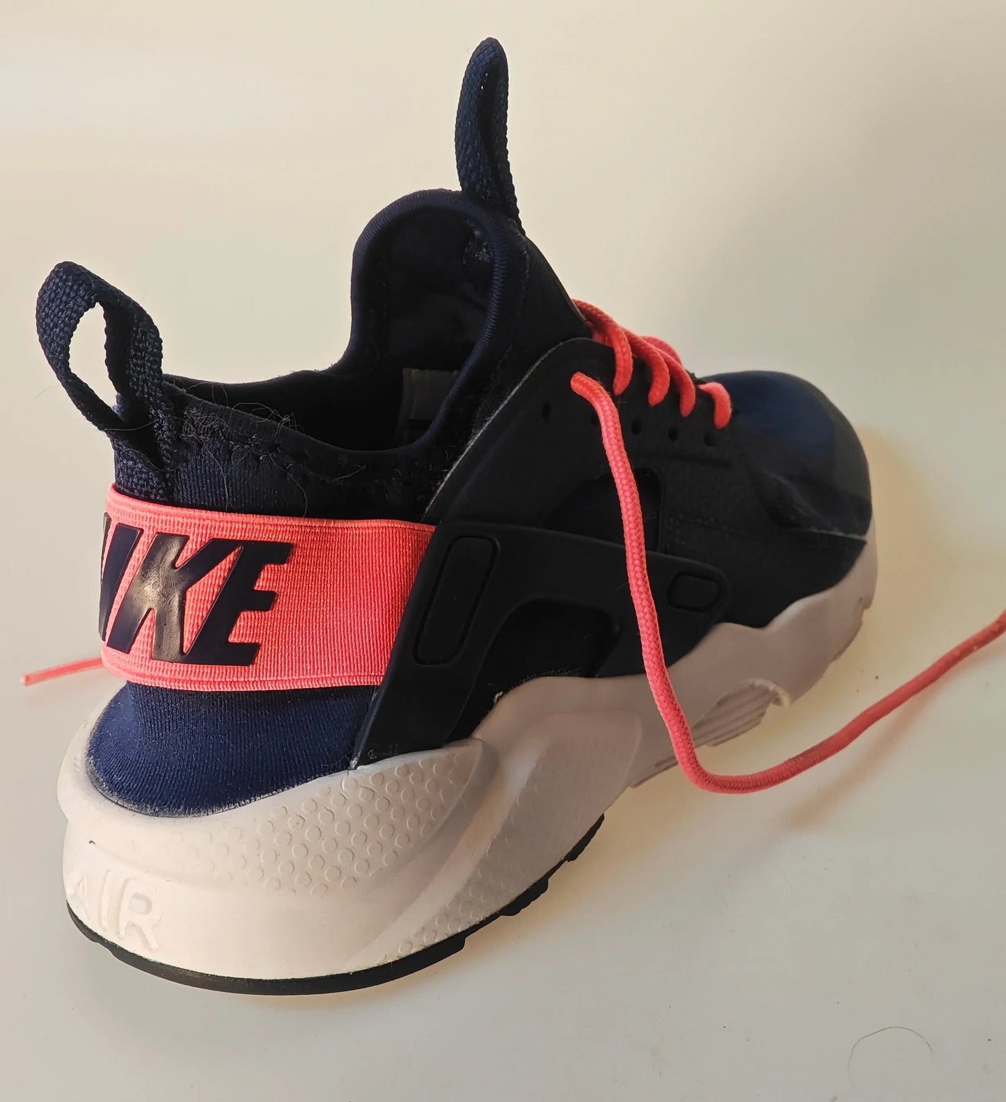 Baskets Nike Air Huarache Run bleu marine et rose de Nike, avec lacets corail et semelle blanche.