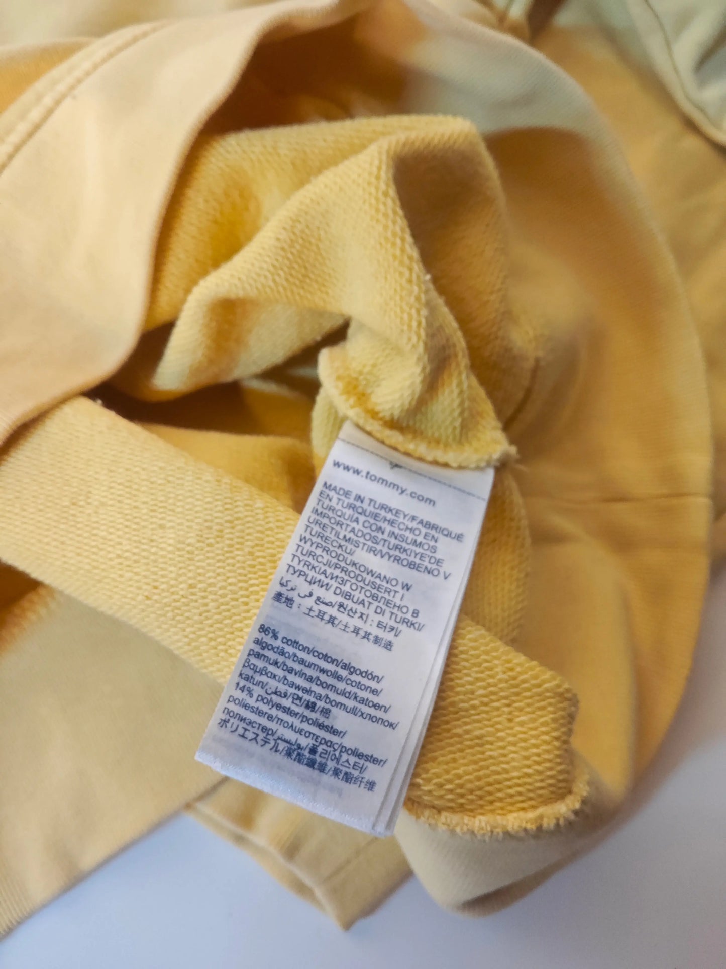 Sweat-shirt jaune en coton par Tommy Hilfiger, avec étiquette d'entretien visible.